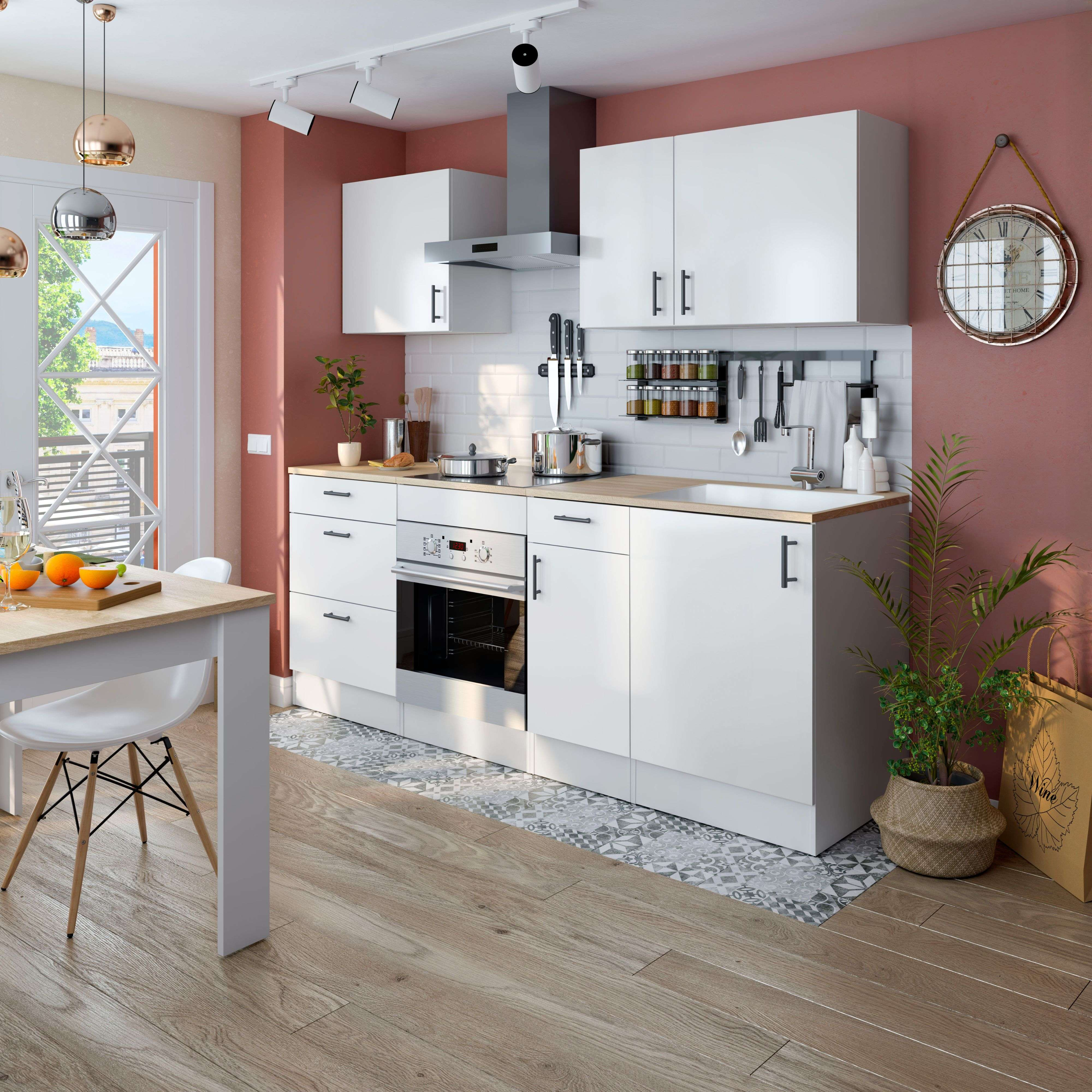 Cocina moderna con gabinetes blancos, encimera de madera y mesa.
