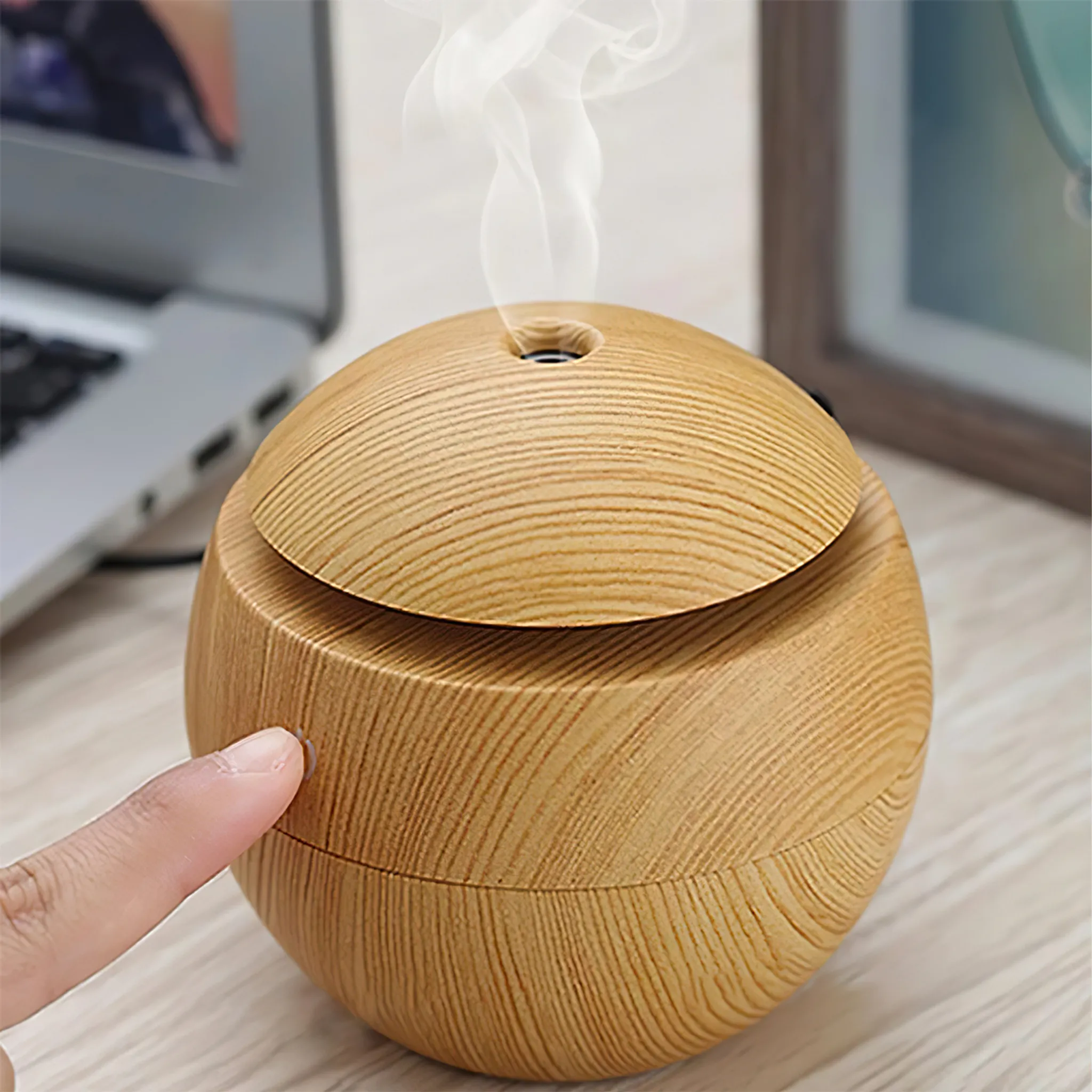 Ein holzfarbener Diffusor gibt Dampf ab, während ein Finger ihn berührt.