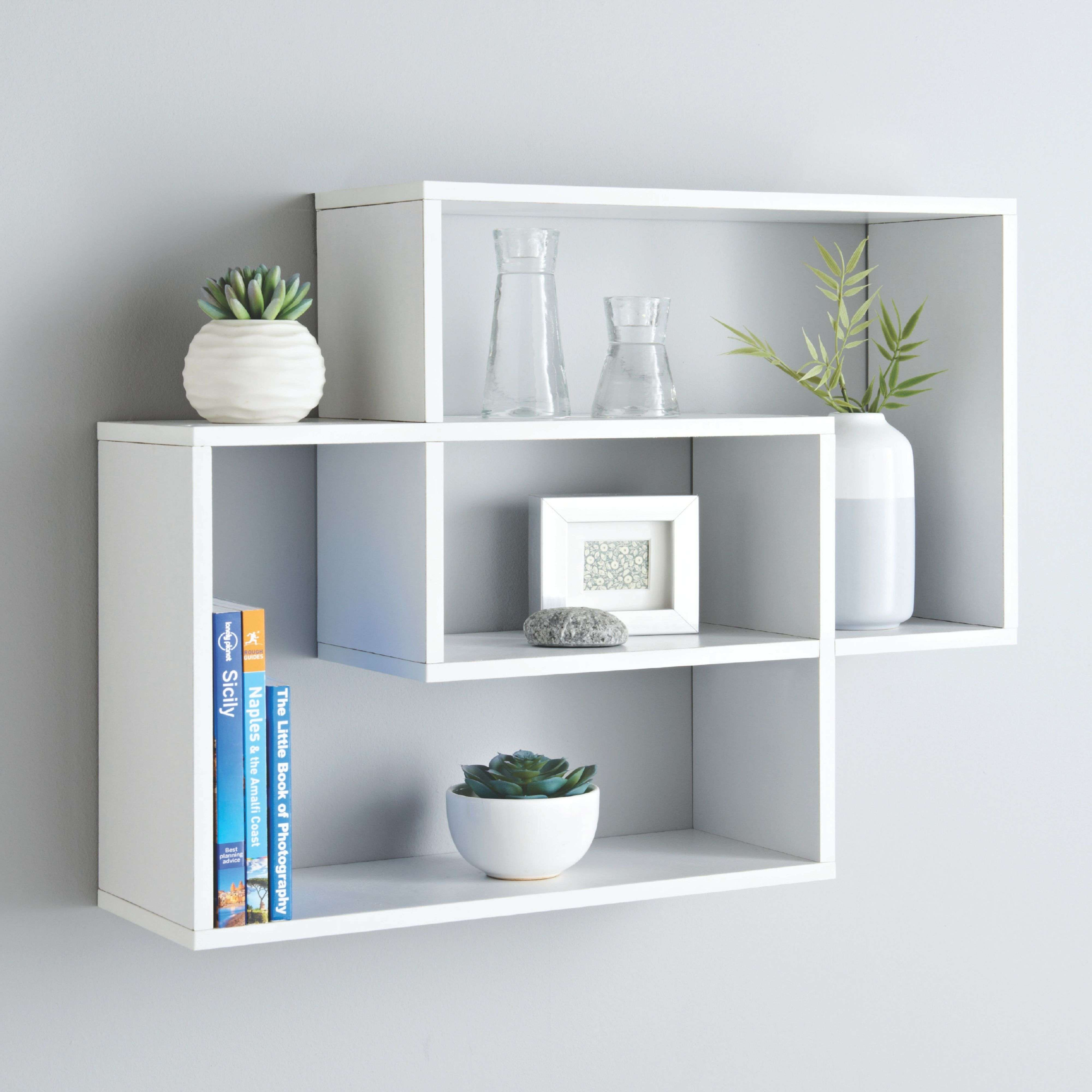 Estantes blancos exhiben artículos decorativos como jarrones, plantas y libros.