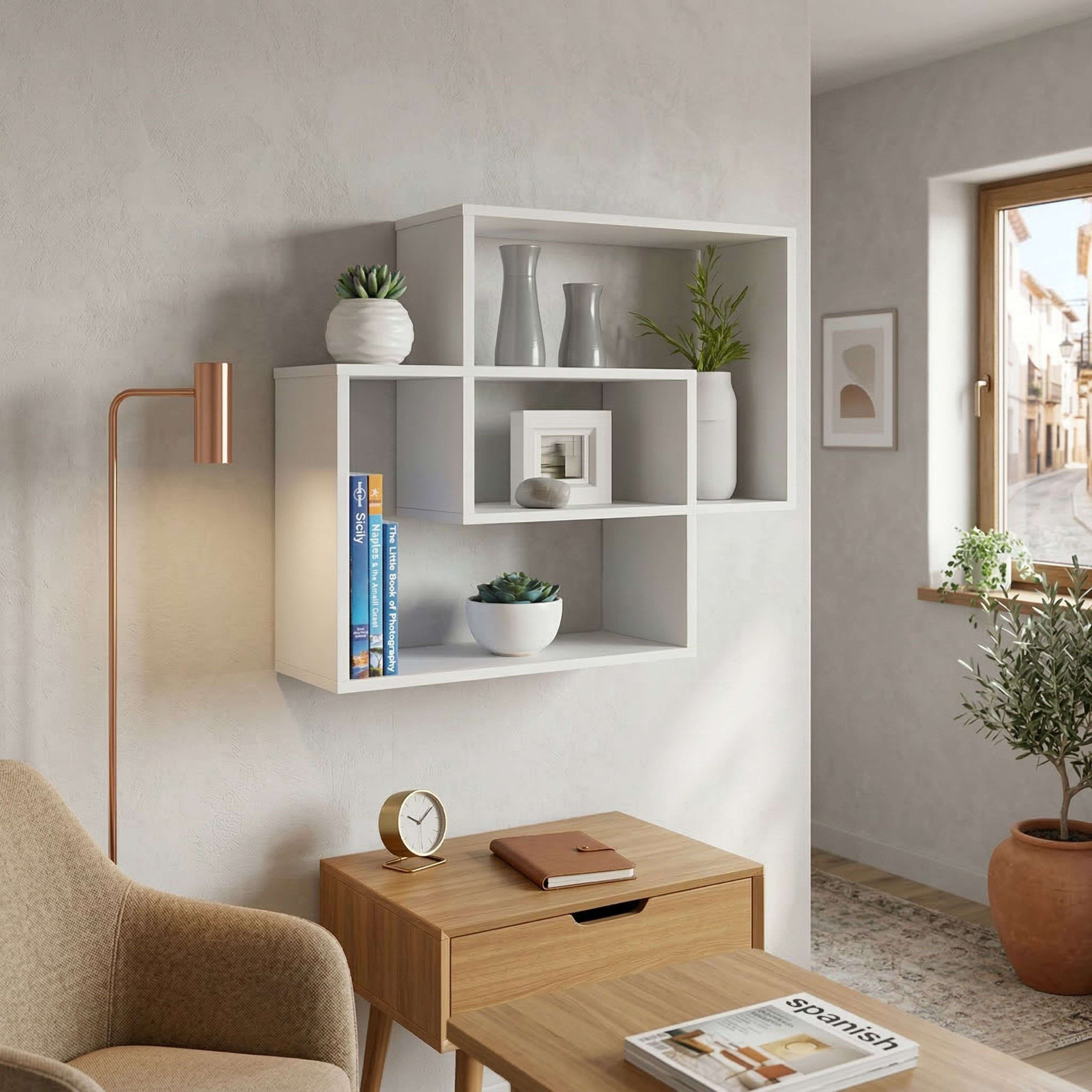 Una estantería blanca de pared con artículos de decoración, junto a un sillón y una mesa.