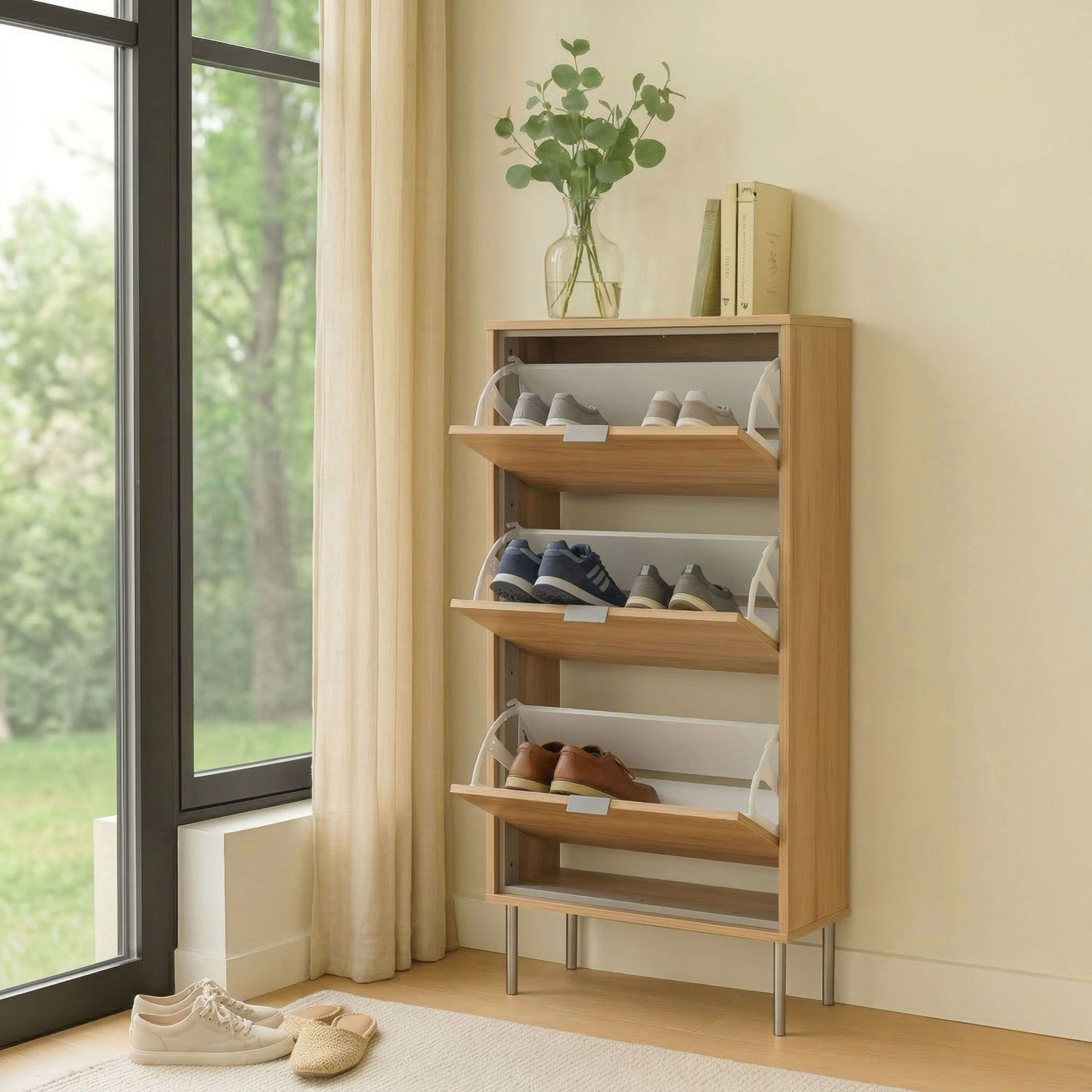 Un estrecho zapatero de madera con tres compartimentos abatibles junto a una ventana.