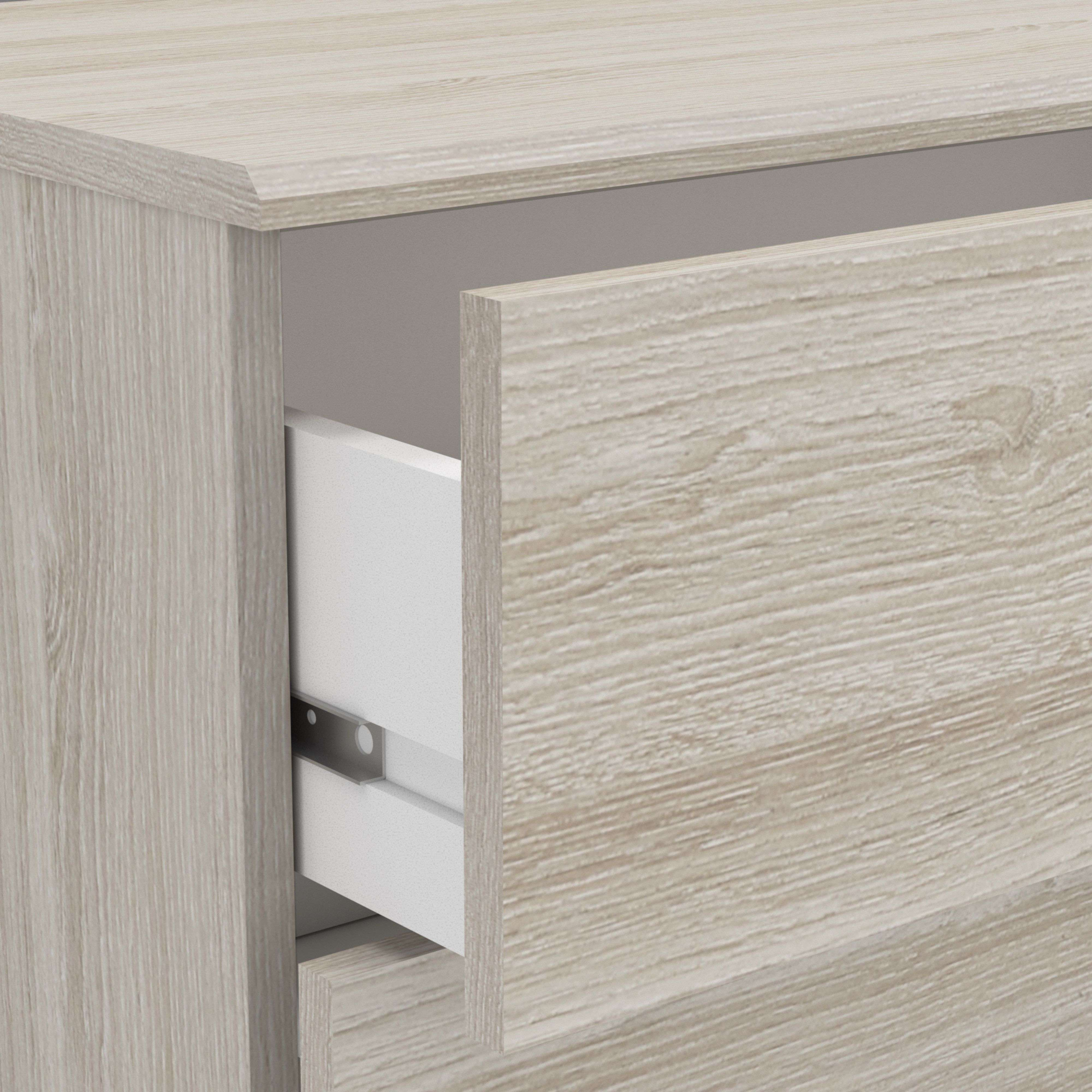 Primer plano de una cómoda de madera clara con un cajón ligeramente abierto.