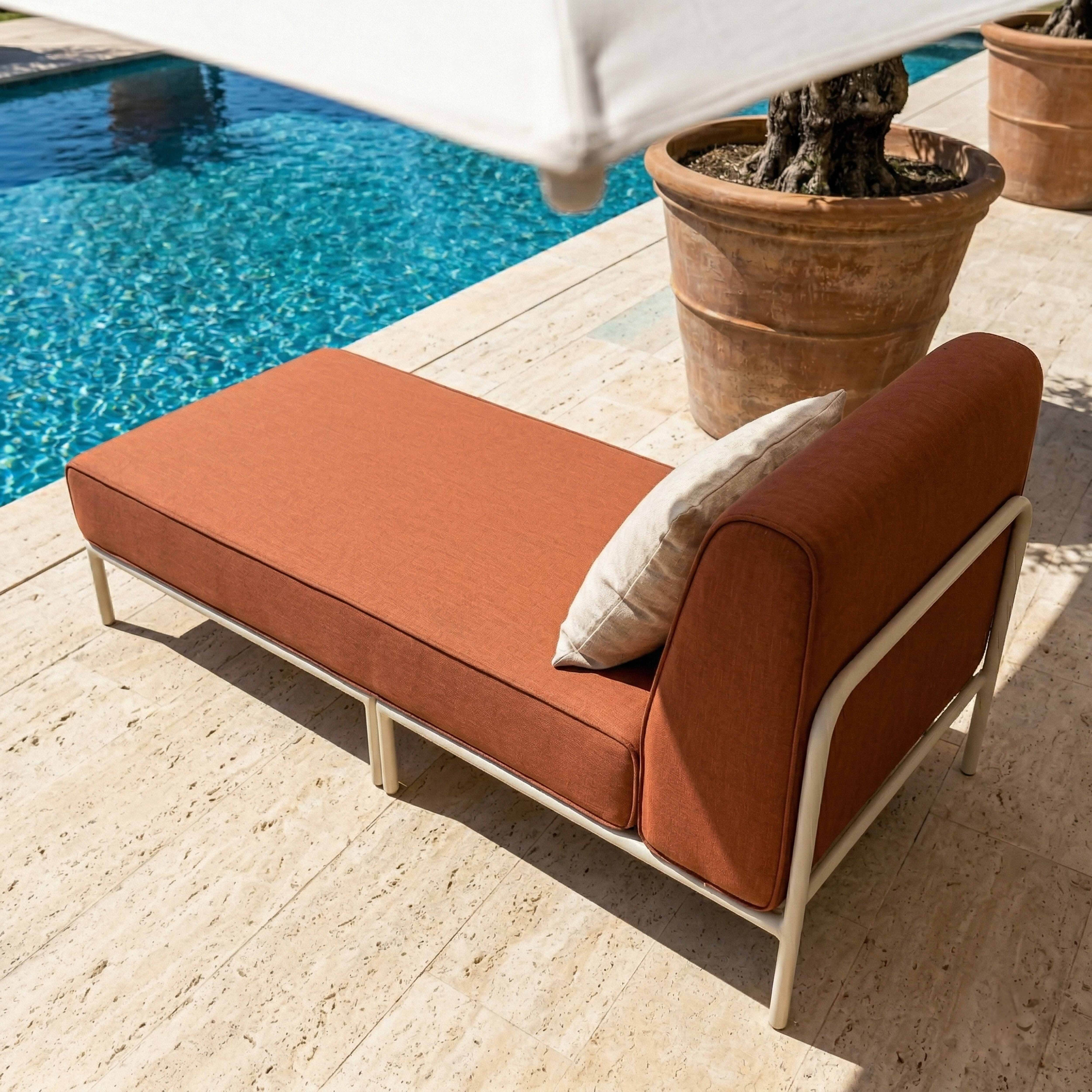 Ein orangefarbener Loungesessel steht neben einem Pool auf einer Steinveranda.