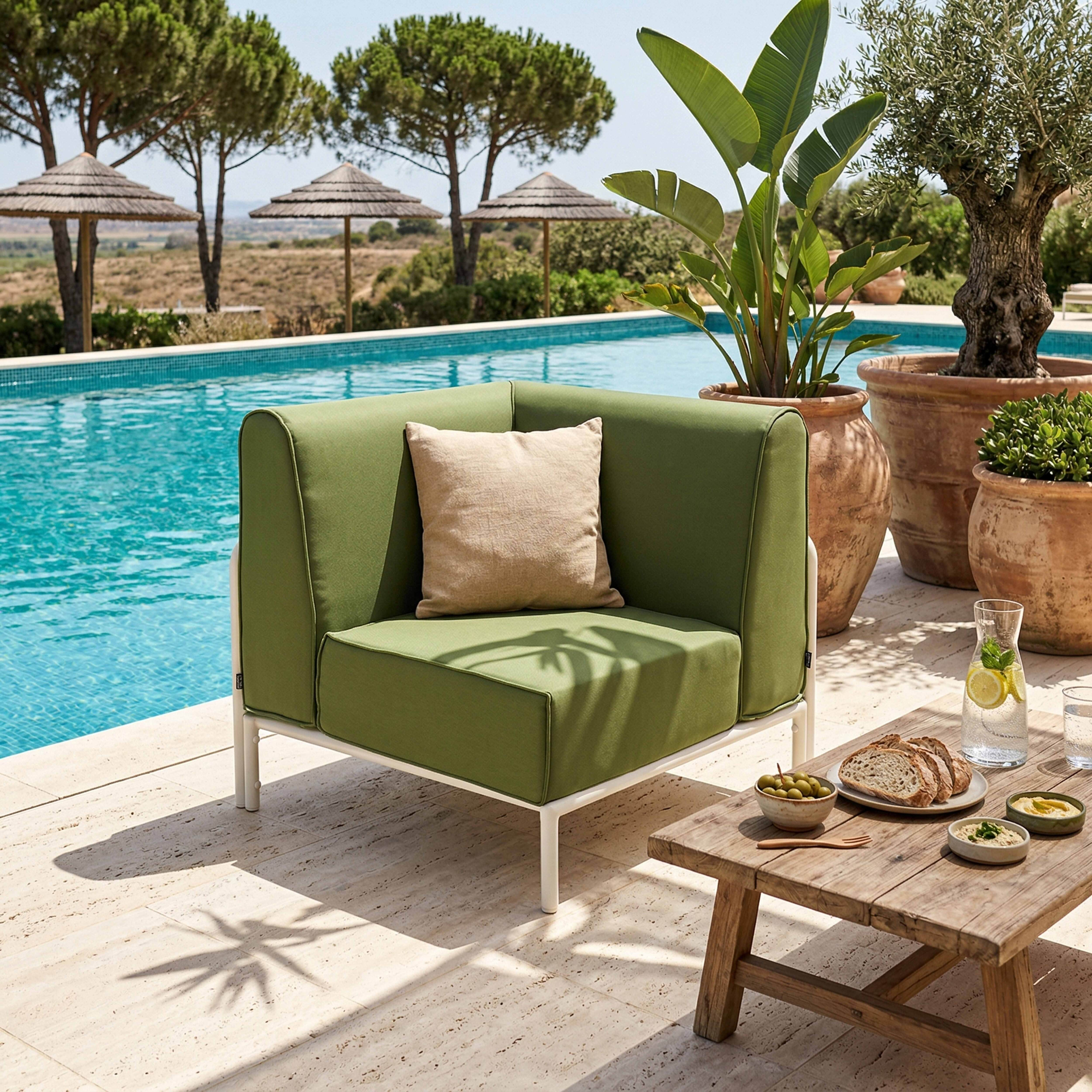 Grüner Sessel am Pool mit Getränken und Snacks auf einem Holztisch.