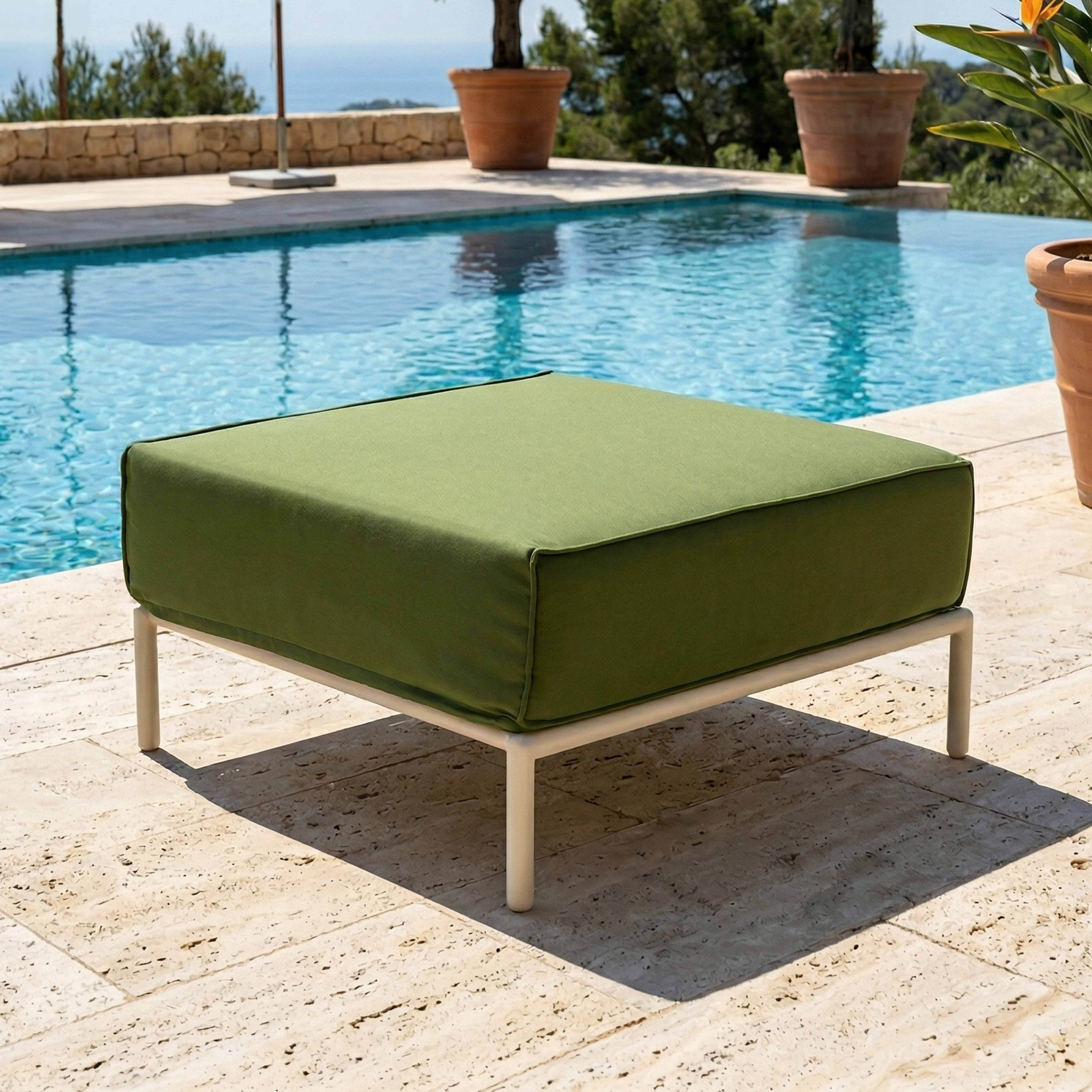 Ein grüner Hocker mit weißem Rahmen steht auf einer Steinplatte neben einem Pool.