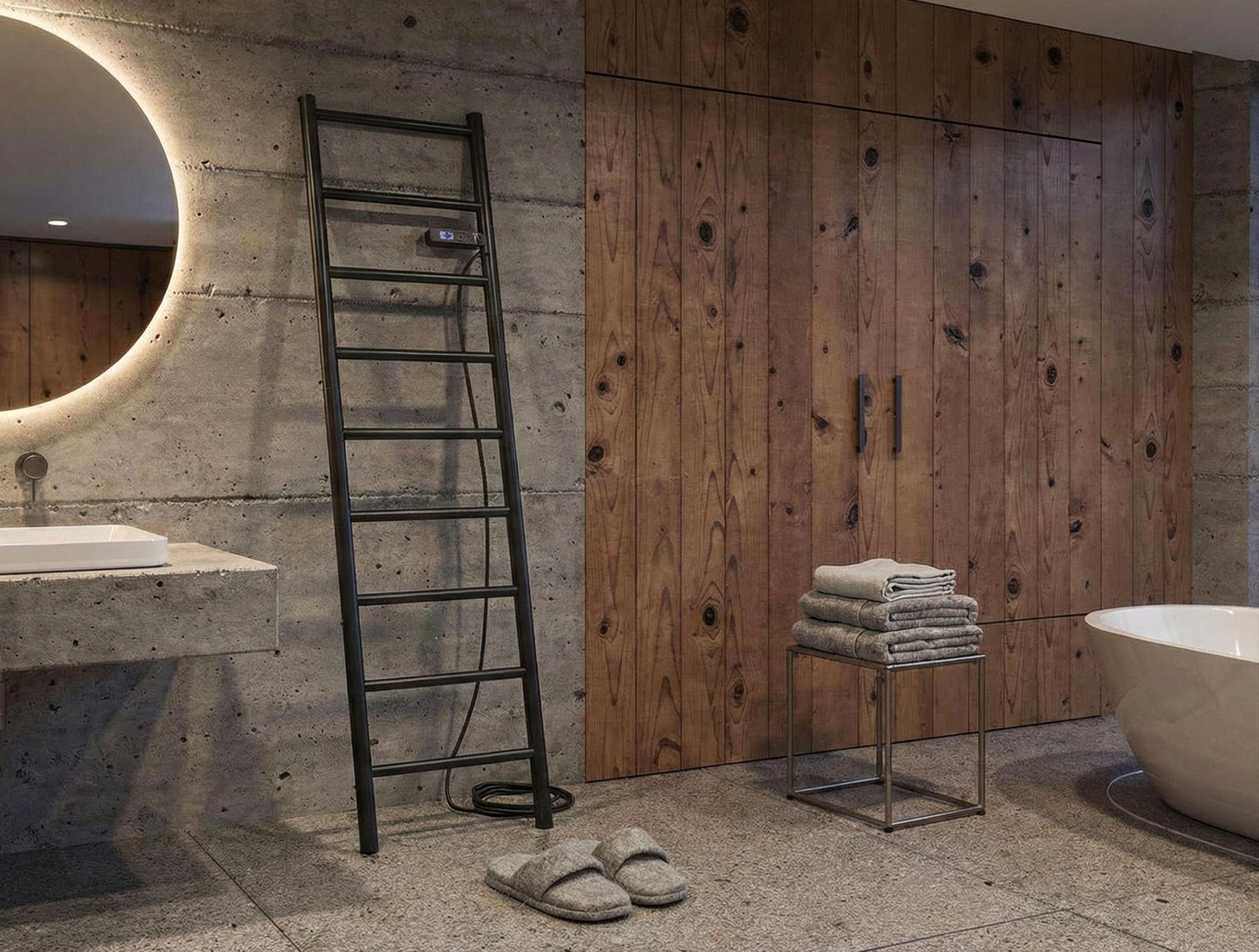 Baño moderno con paredes de hormigón, puertas de madera, toallero, bañera y zapatillas.