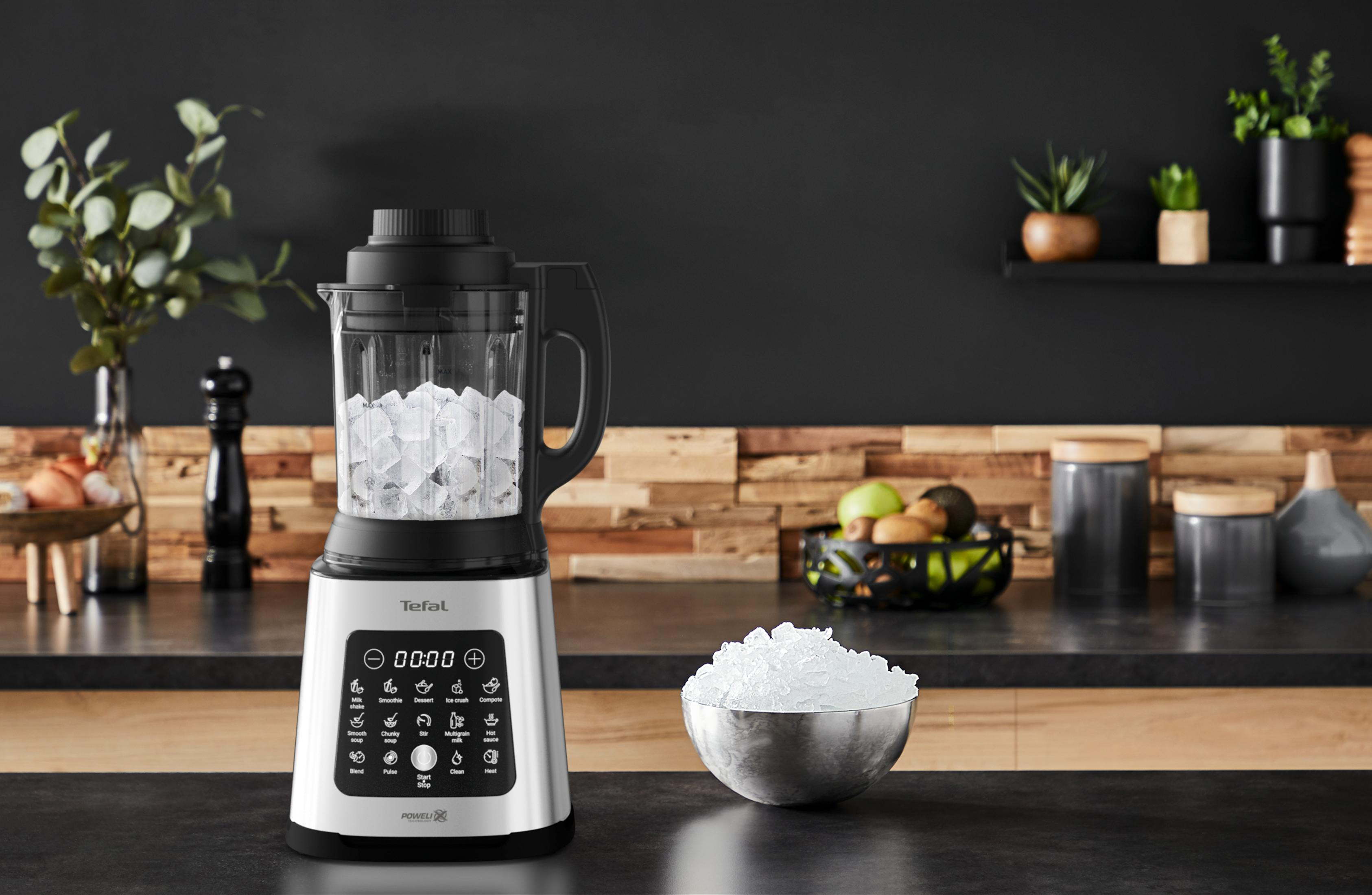 Ein silberner Tefal-Standmixer mit Eiswürfeln, daneben eine Schale mit zerstoßenem Eis.