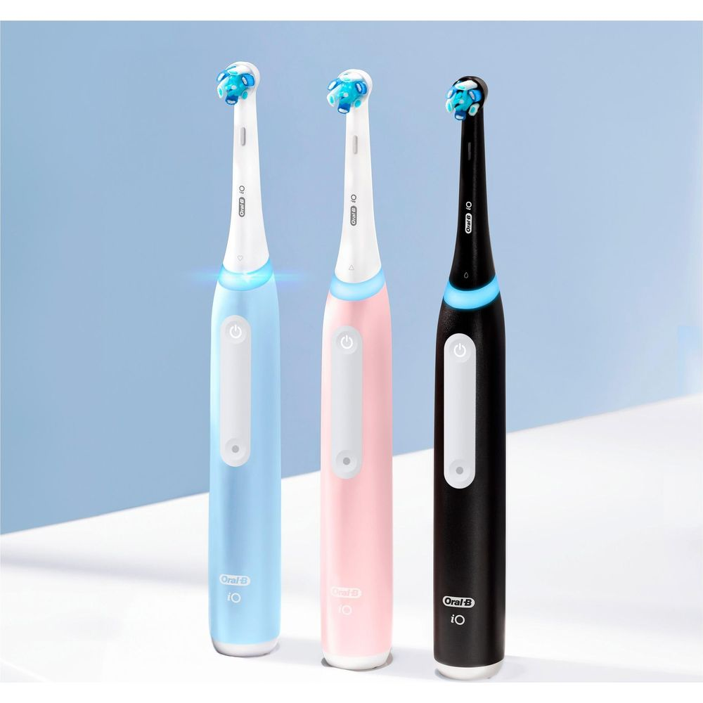 Drei elektrische Zahnbürsten: blau, rosa und schwarz, nebeneinander.