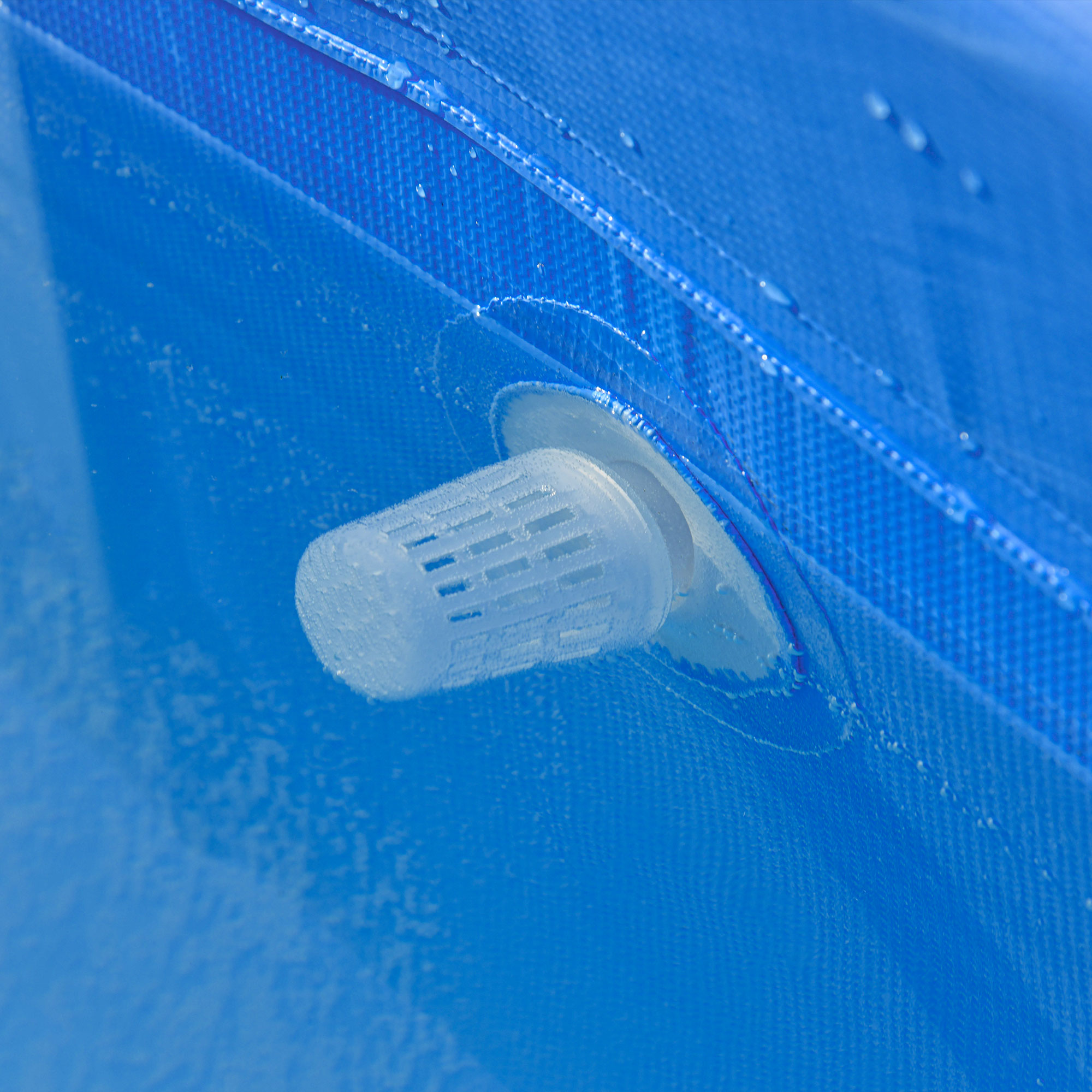 Primer plano de material texturizado azul con válvula de ventilación transparente.