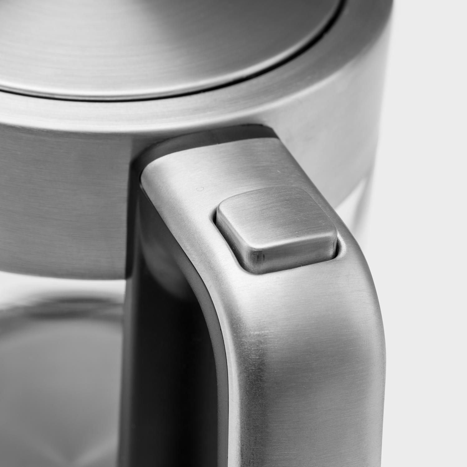 A silver button on a brushed metal kettle handle.