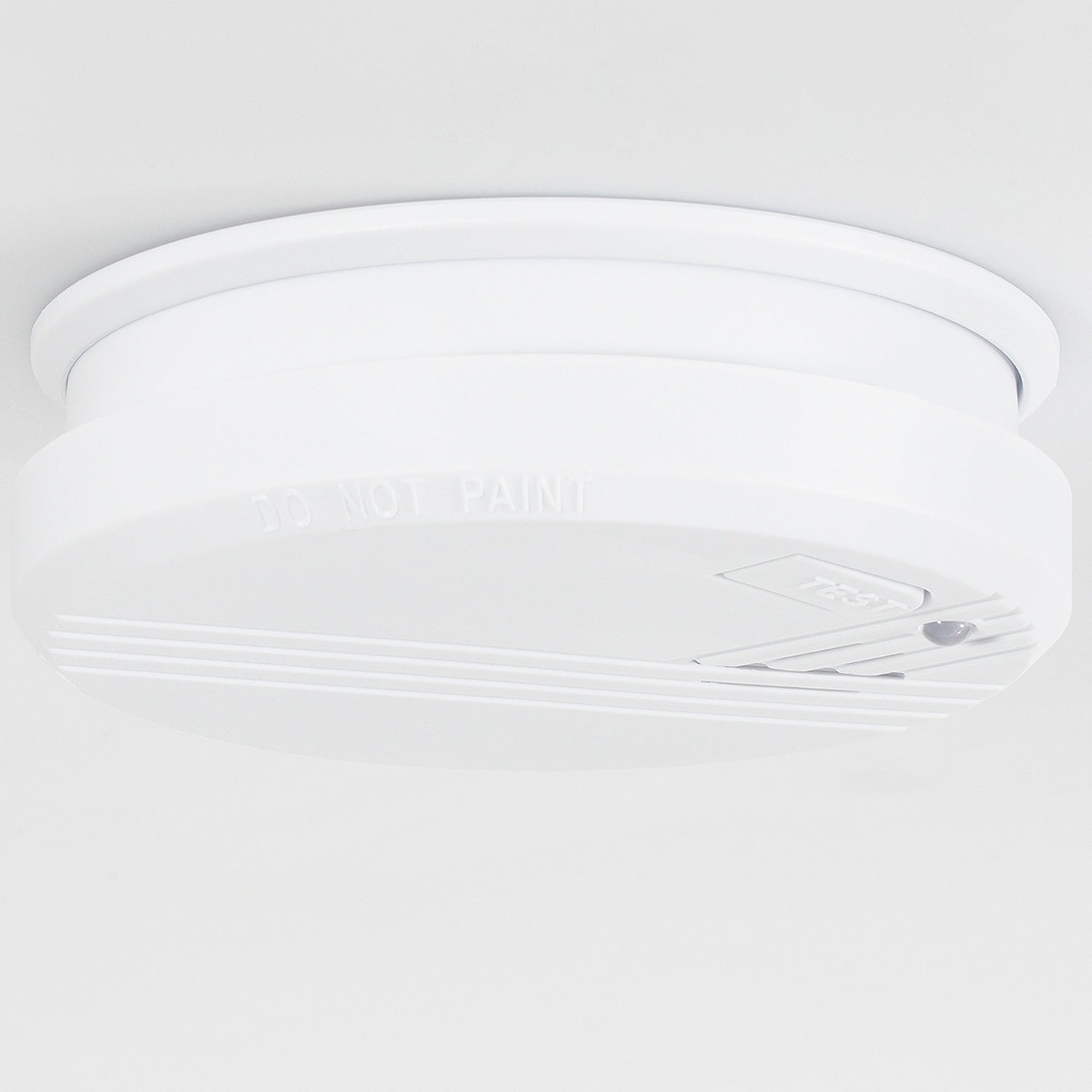 A white smoke detector is mounted on the ceiling. It has a test button.