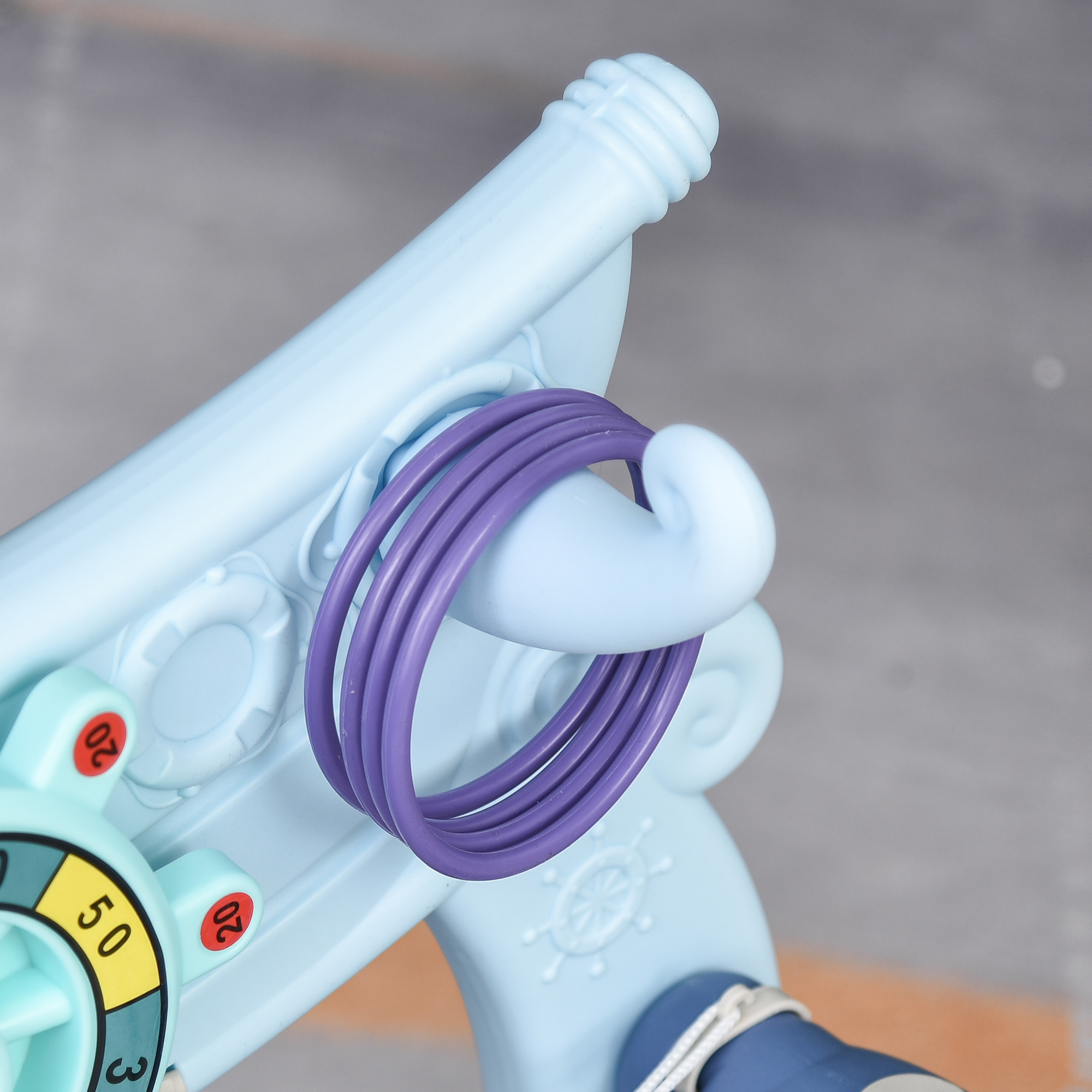 Pistola de juguete azul claro con anillos púrpuras sobre el cañón.