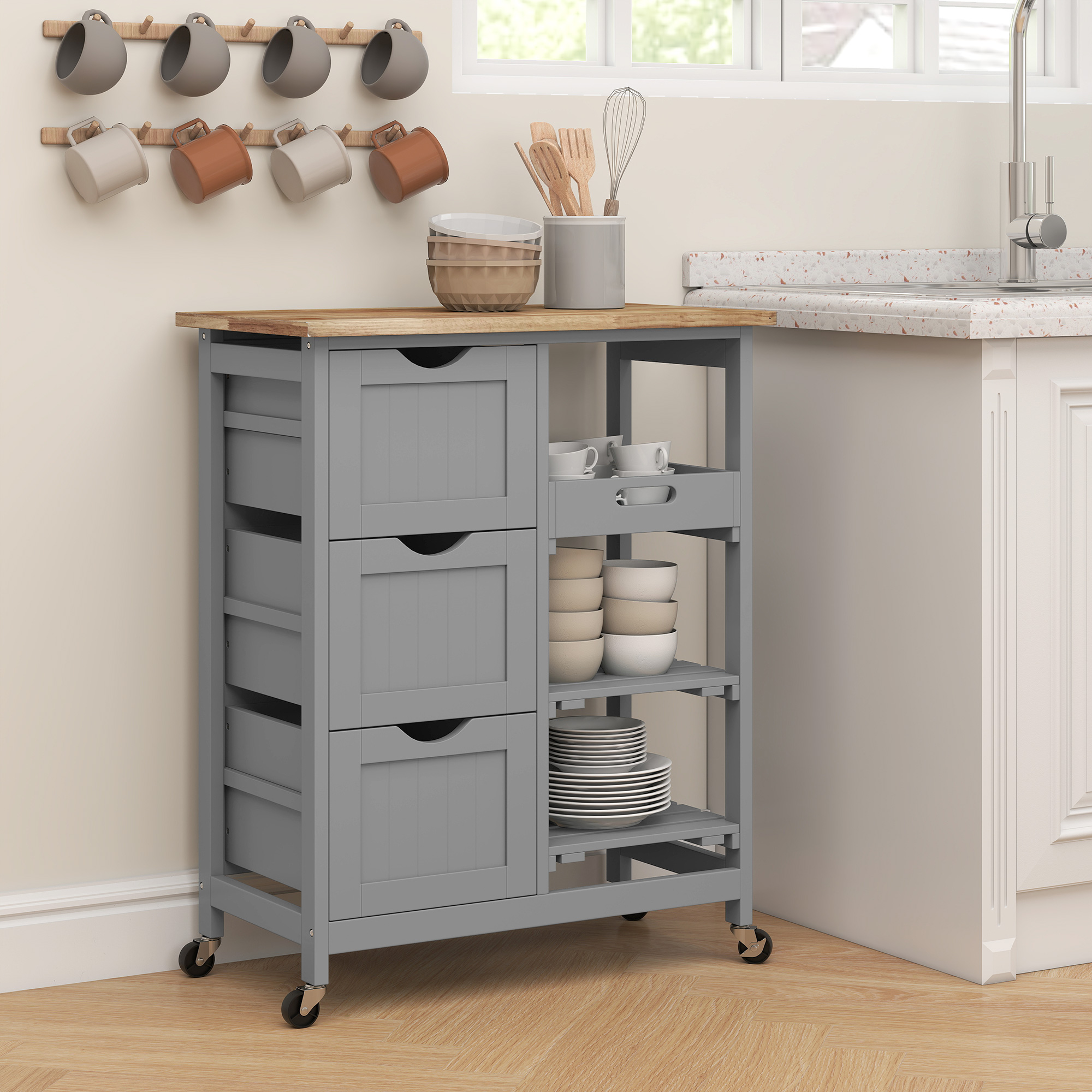 Carro de cocina gris con tapa de madera, cajones y estantes llenos de platos.