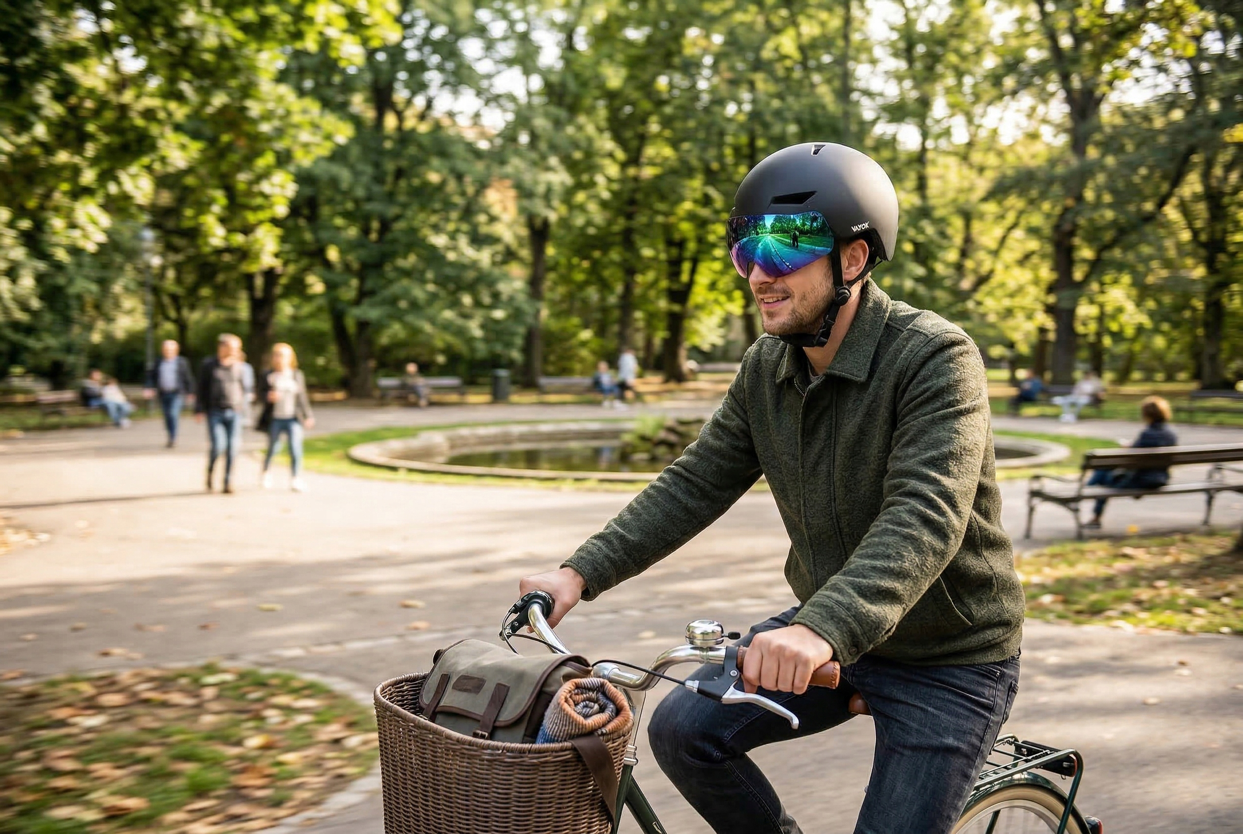 Mężczyzna jedzie rowerem w parku, w kasku i okularach, koszyk z kocem.