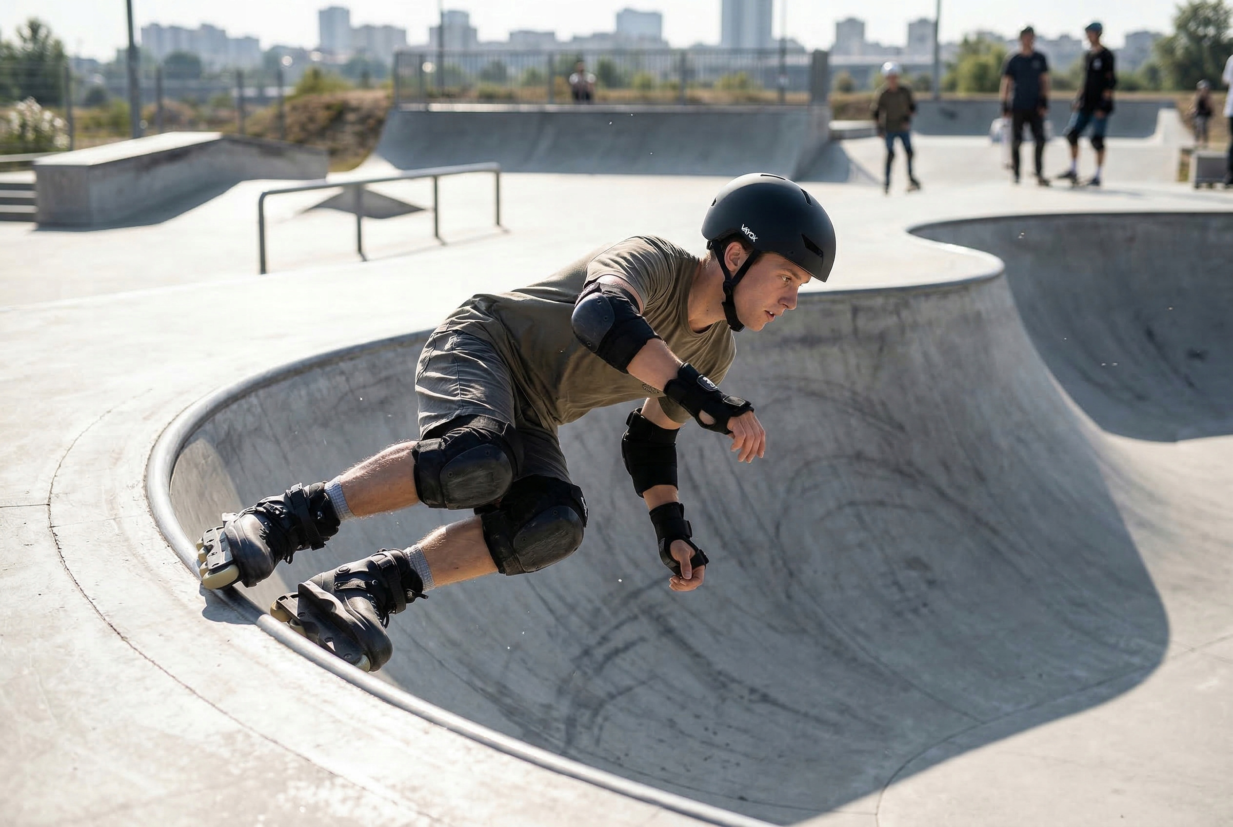 Mężczyzna w kasku jeździ na rolkach po betonowej rampie, inni jeżdżą w tle.