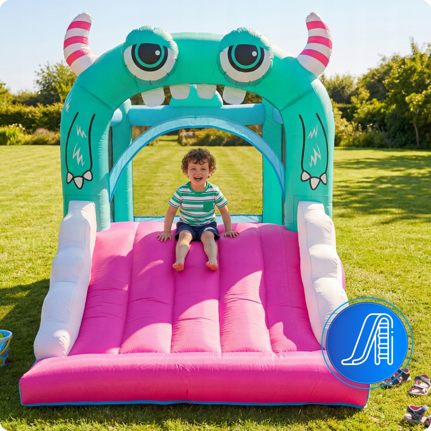 Ein Kind lacht auf einer aufblasbaren Monster-Rutsche im Garten.