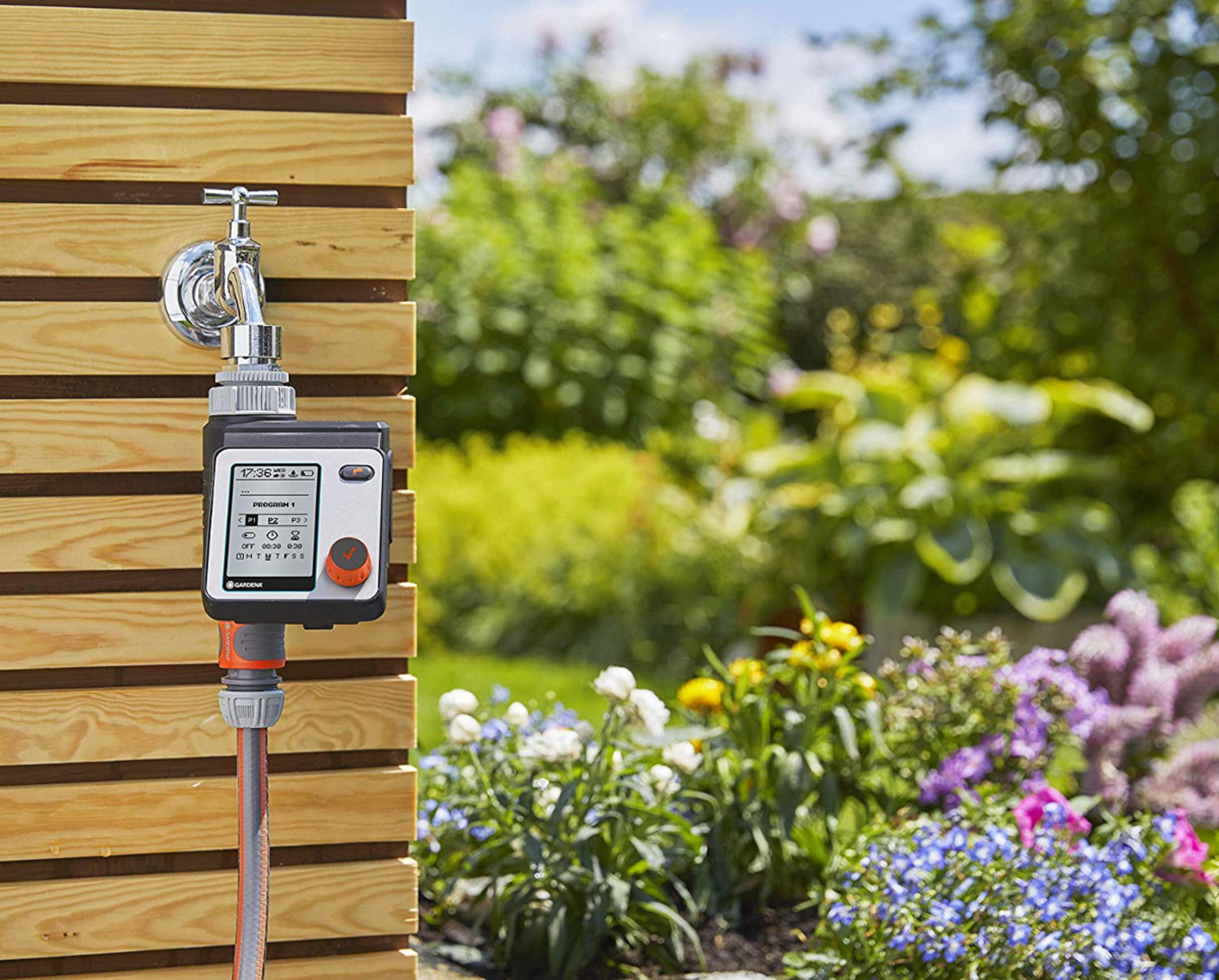 Un timer per tubo da giardino è attaccato a un rubinetto su una parete di legno.