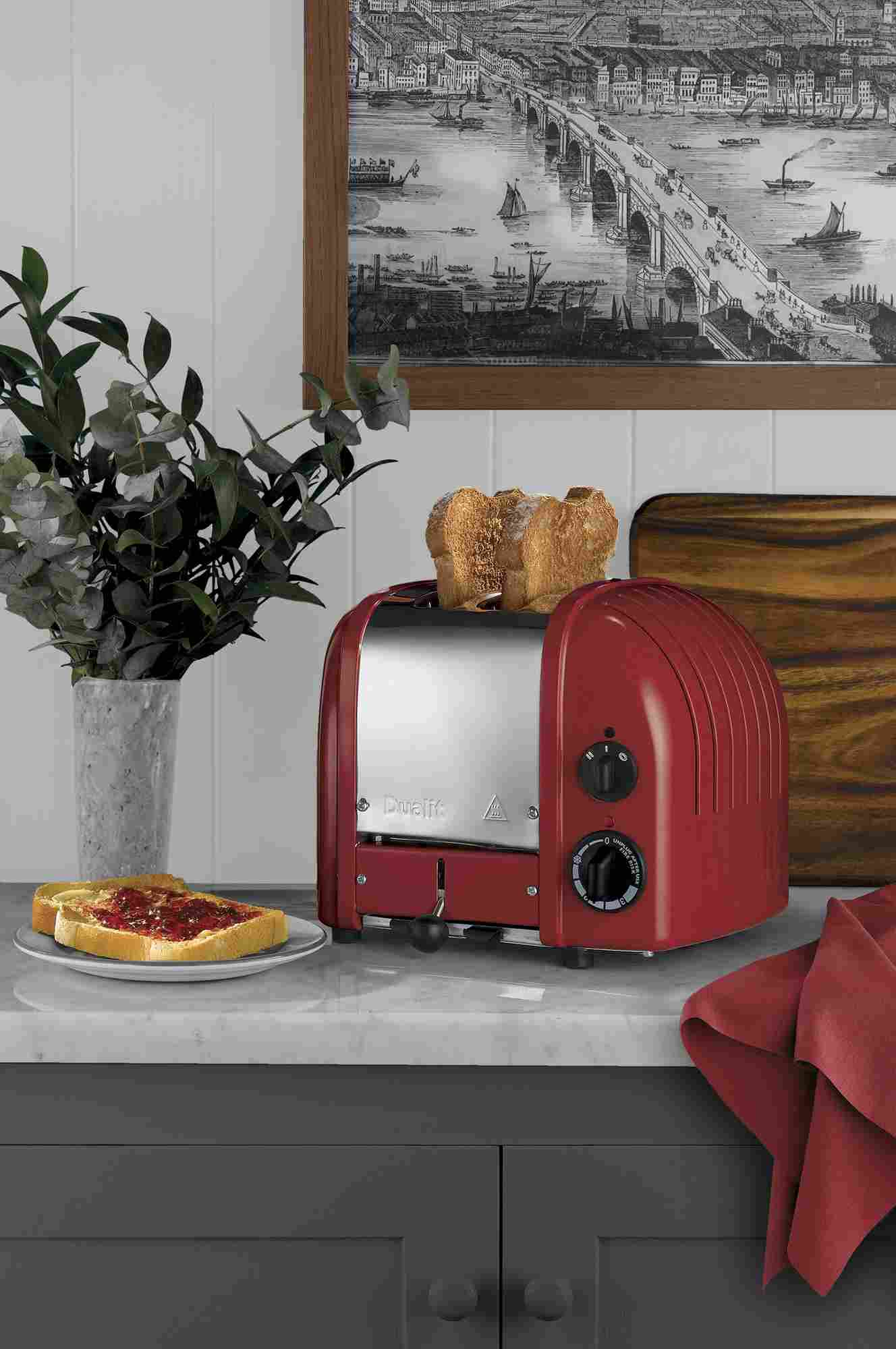 Ein roter Toaster mit Toast und Marmelade auf einem Teller.
