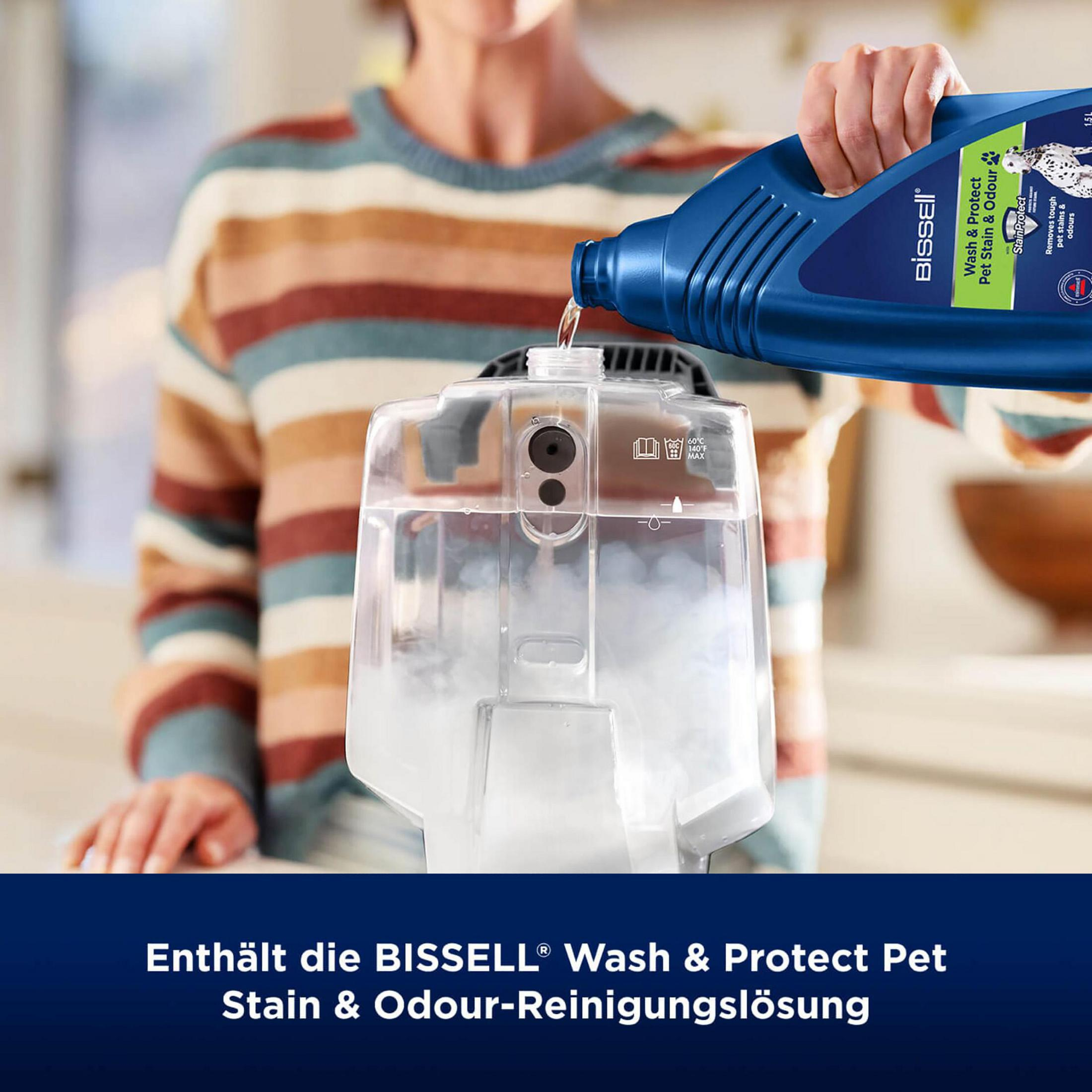 Eine Person gießt eine blaue Flüssigkeit aus einer Flasche in einen transparenten Behälter.