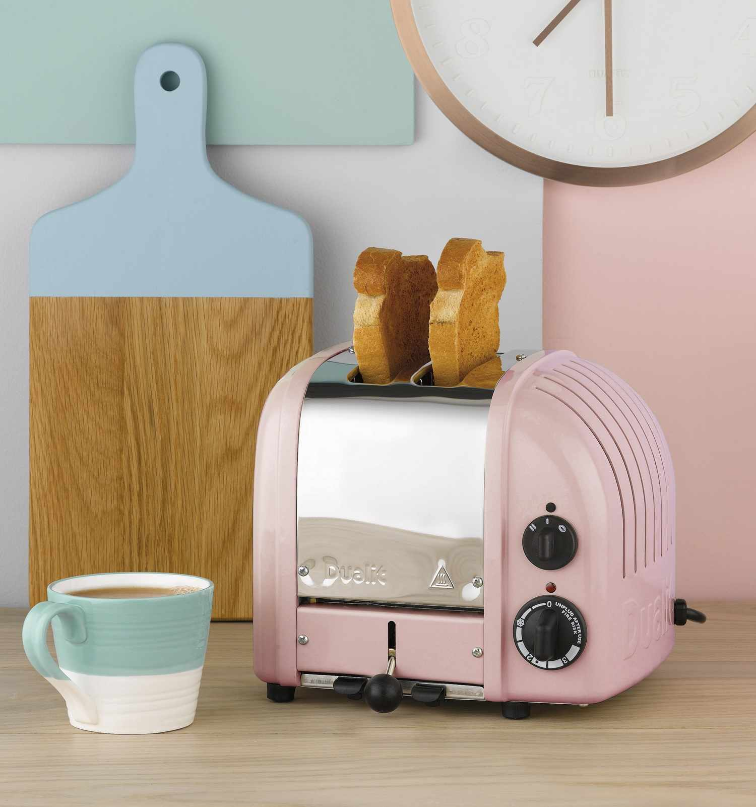 Ein rosafarbener Toaster mit zwei Toastscheiben und einer Tasse Kaffee.