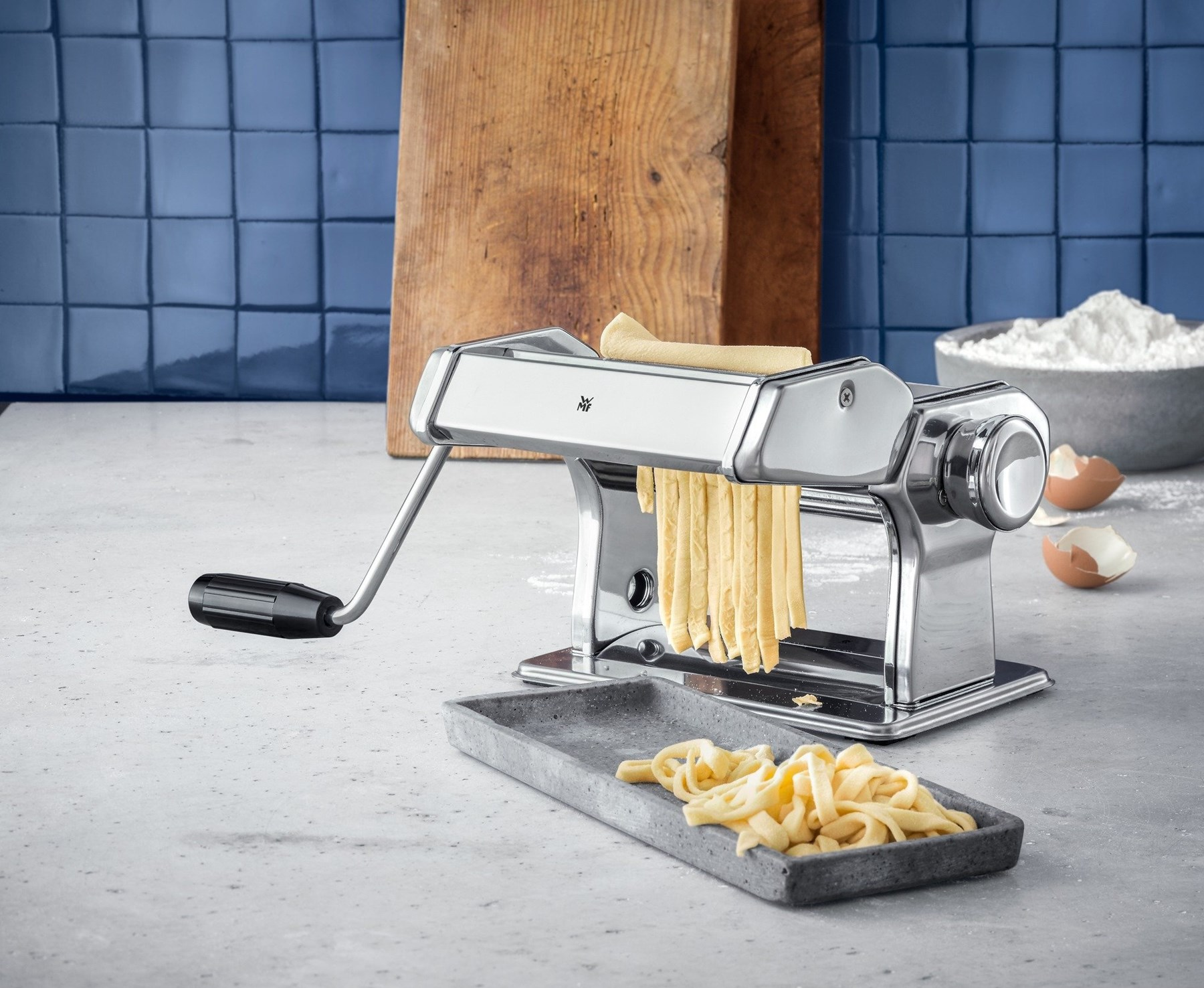 Eine Nudelmaschine stellt frische Pasta her, daneben liegen fertige Nudeln.