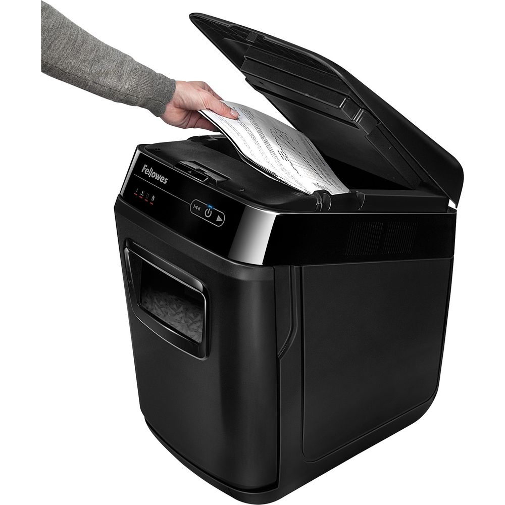 Eine Hand führt Papier in einen schwarzen Fellowes-Aktenvernichter ein.