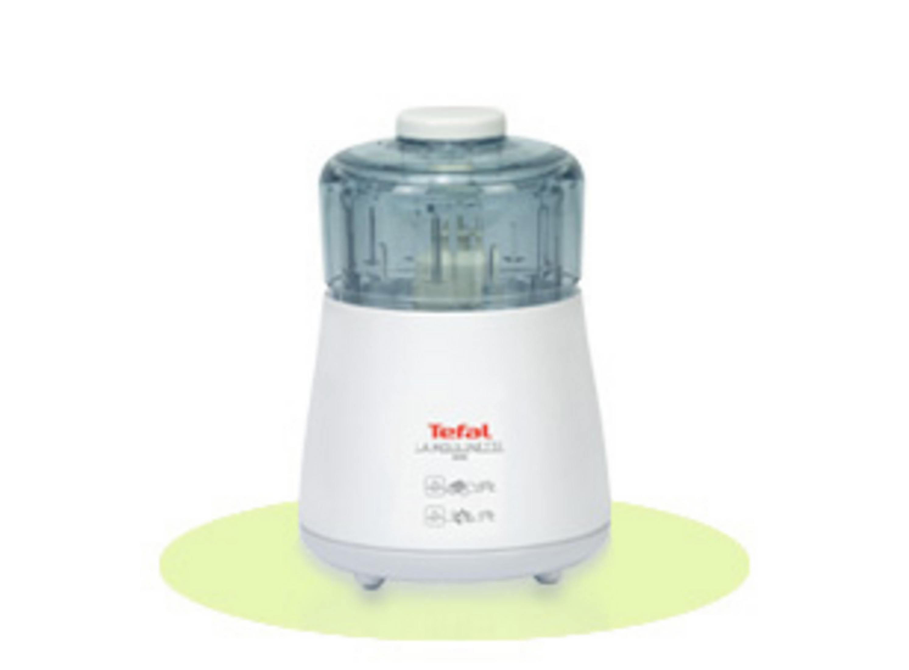 Un mini tritatutto bianco Tefal con coperchio trasparente blu è su un ovale verde chiaro.
