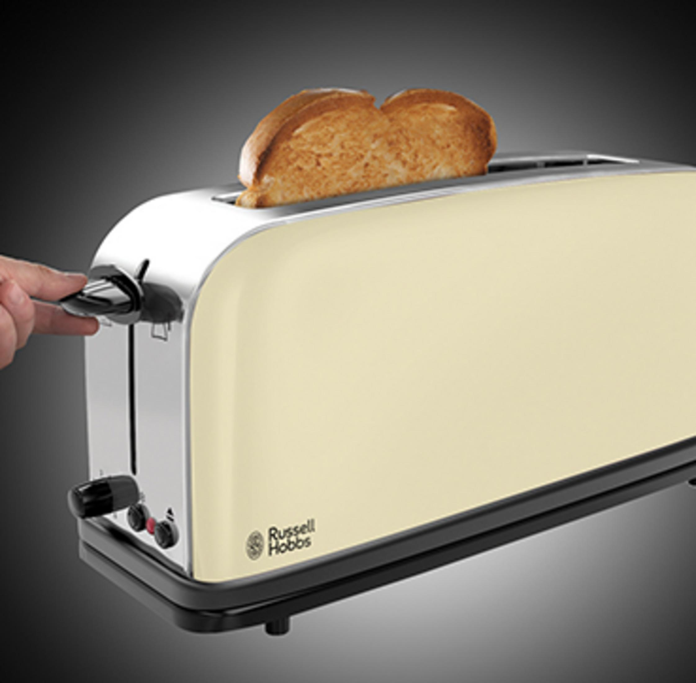 Kremowy toster z dwoma wystającymi kromkami chleba. Ręka obsługuje dźwignię.