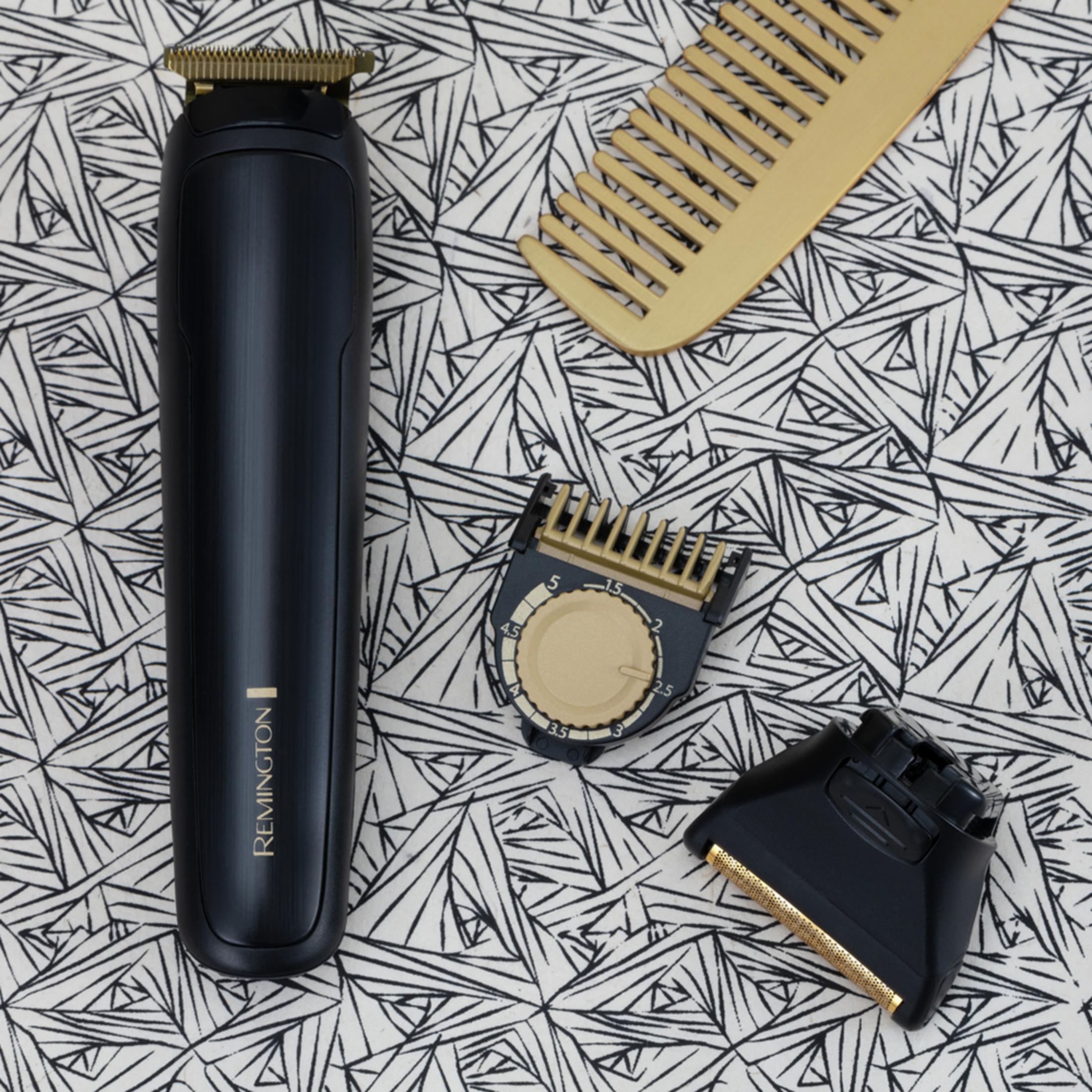 Ein schwarzer Remington-Trimmer mit goldenen Akzenten, Kamm und Aufsätzen auf gemustertem Stoff.