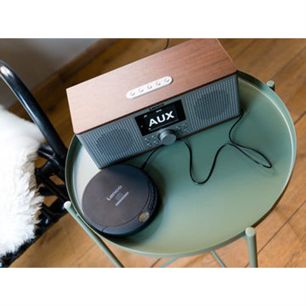 Drewniane radio i odtwarzacz CD stoją na okrągłym, zielonym stole.