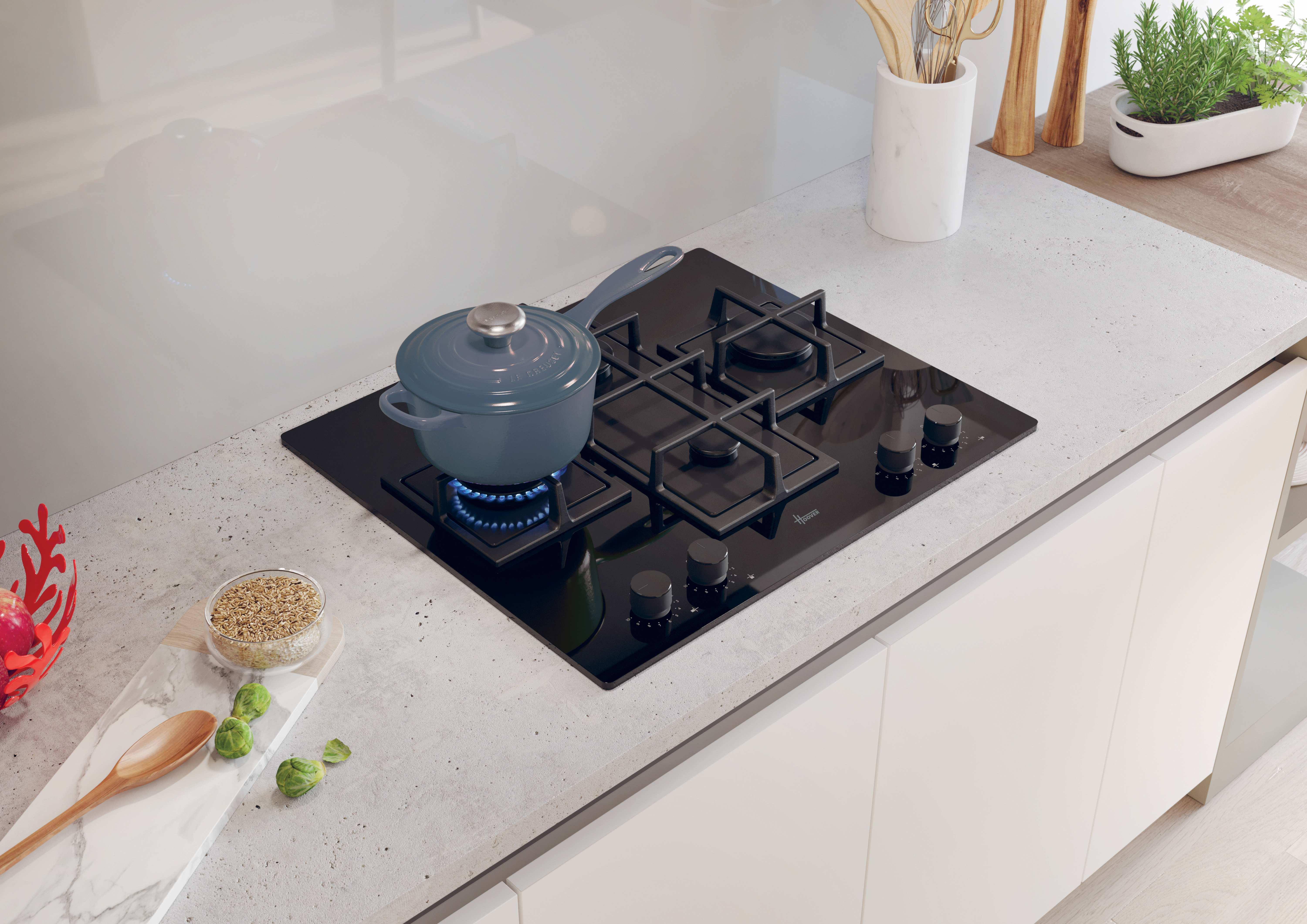 Una pentola blu cuoce su un fornello a gas nero in una cucina moderna.