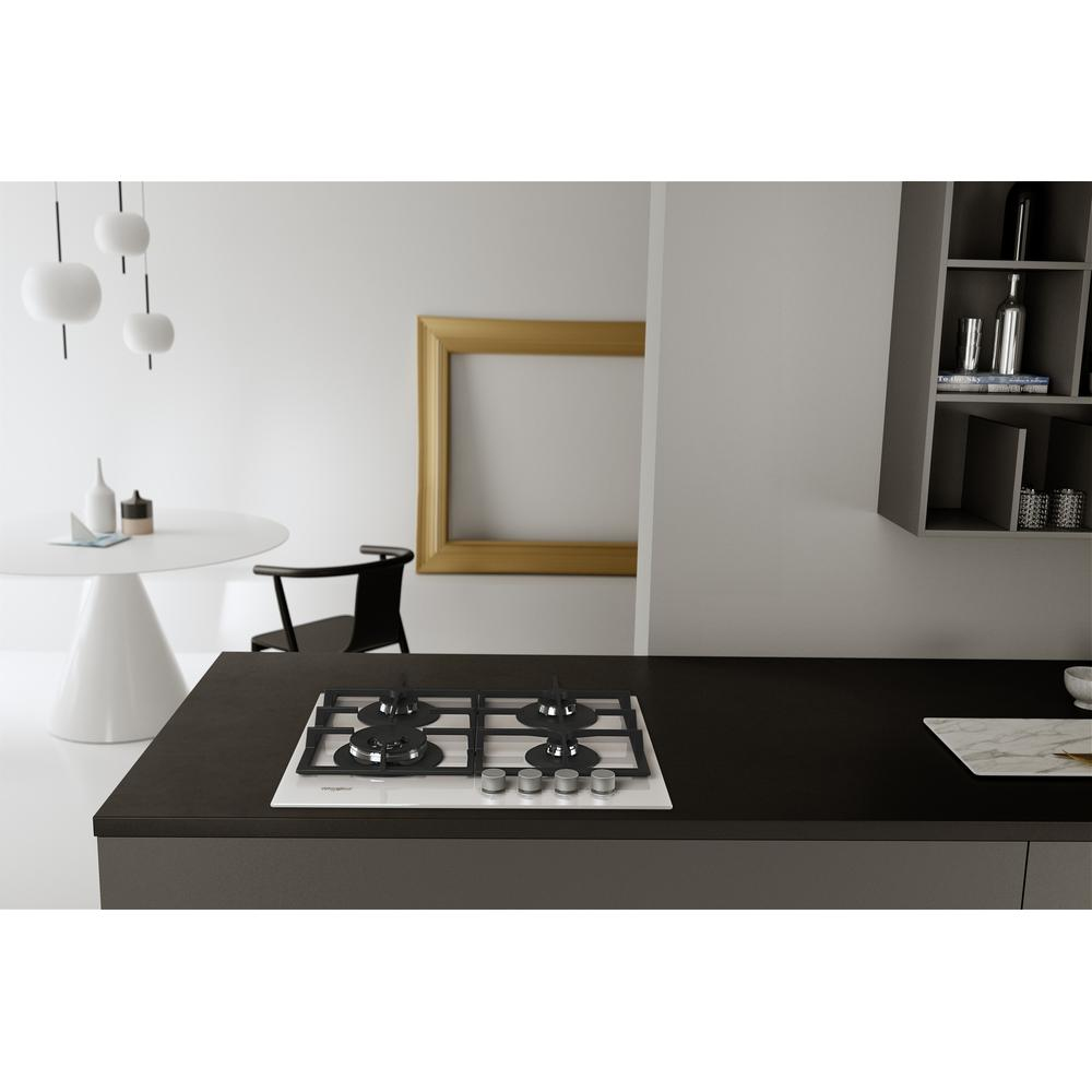Cucina moderna con piano cottura bianco su piano di lavoro scuro, tavolo e mensola.