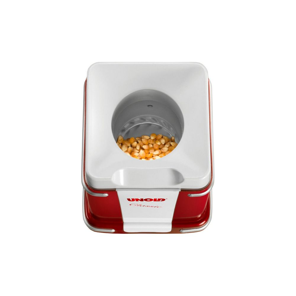 Una máquina de palomitas roja y blanca con granos de maíz en el compartimento superior.