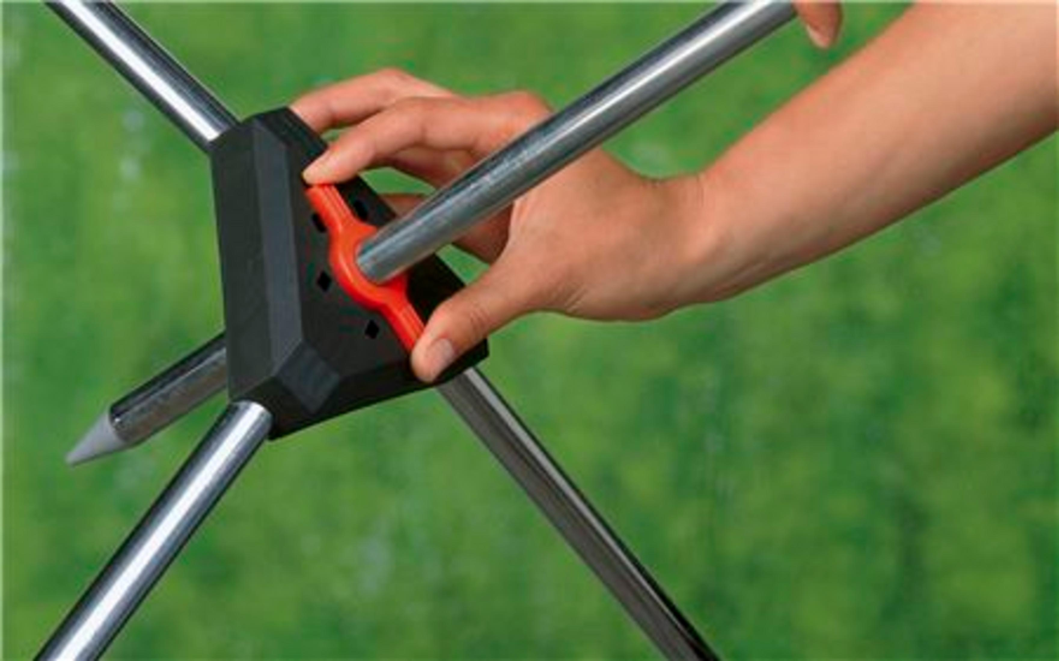 Ręka obsługuje czerwony uchwyt na czarnym urządzeniu z metalowymi prętami.