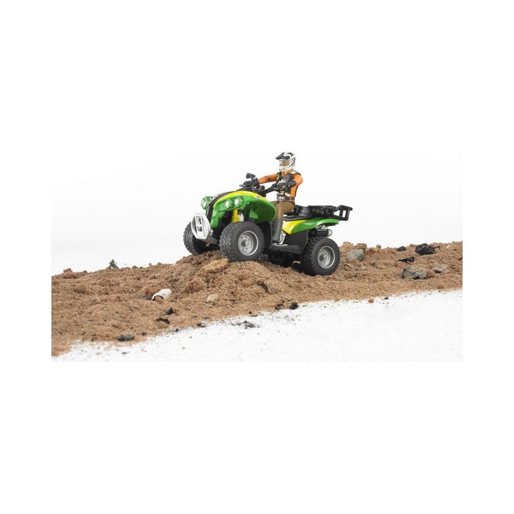 Zielony quad z kierowcą na piaszczystym wzgórzu.