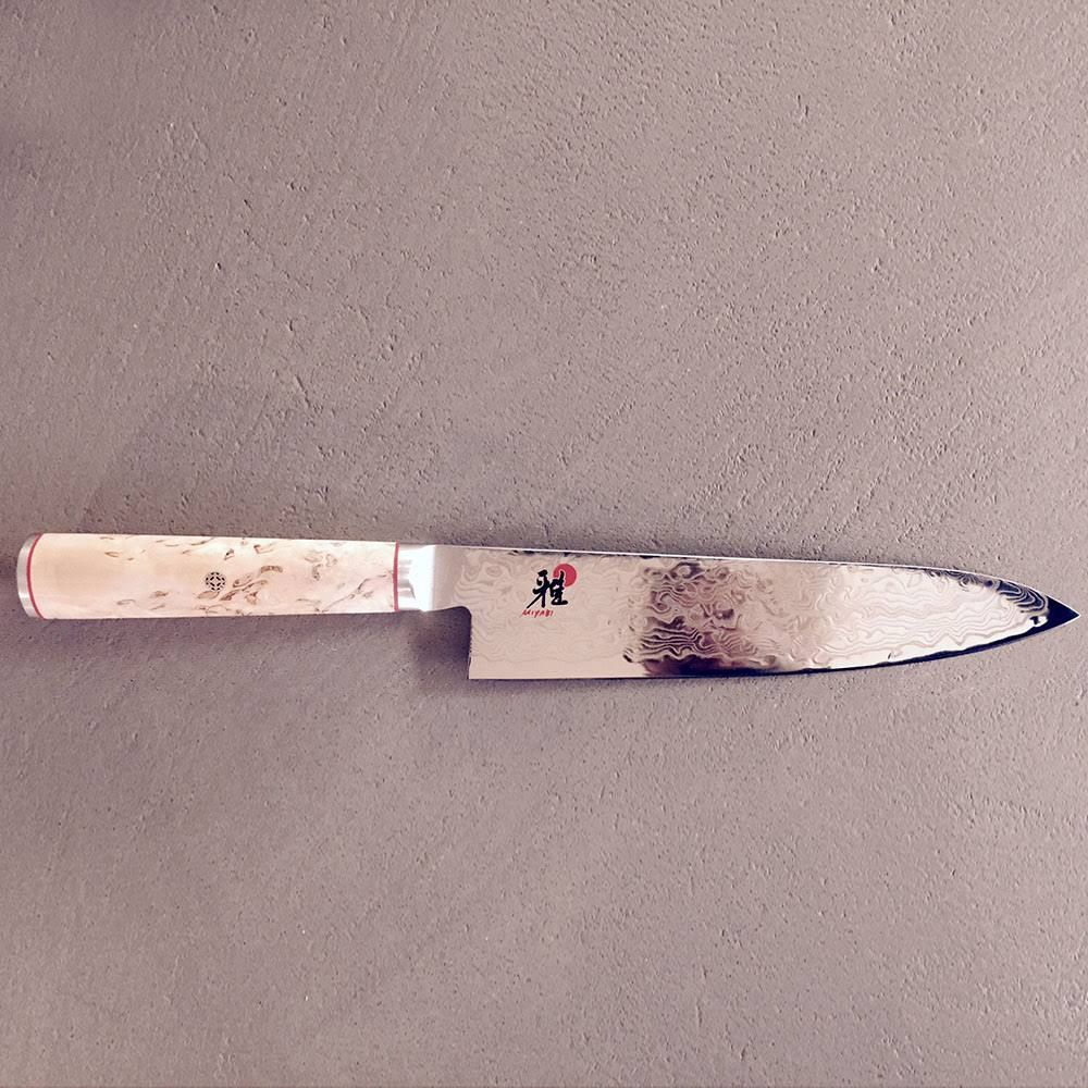Ein scharfes Kochmesser mit Damaststahlklinge und hellem Holzgriff.