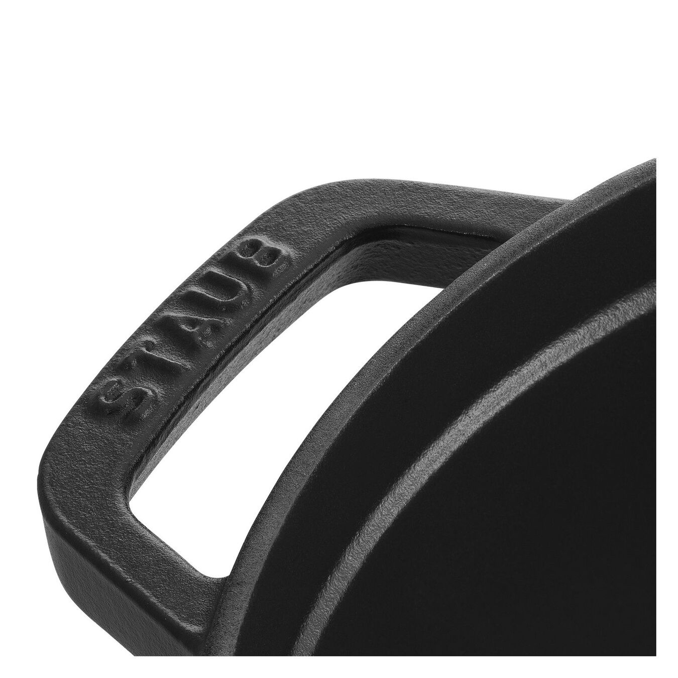 Nahaufnahme des schwarzen Griffs eines Gusseisentopfs mit dem eingeprägten Schriftzug STAUB.