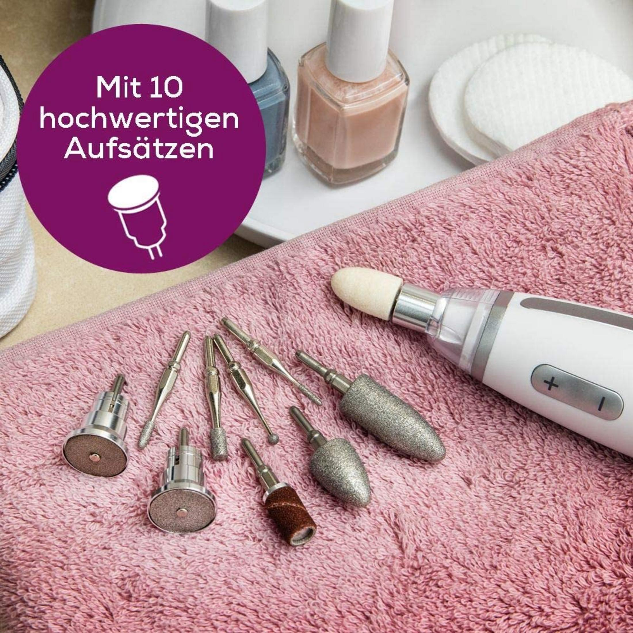 Nagelpflegegerät mit 10 Aufsätzen auf rosa Handtuch, Nagellackflaschen im Hintergrund.