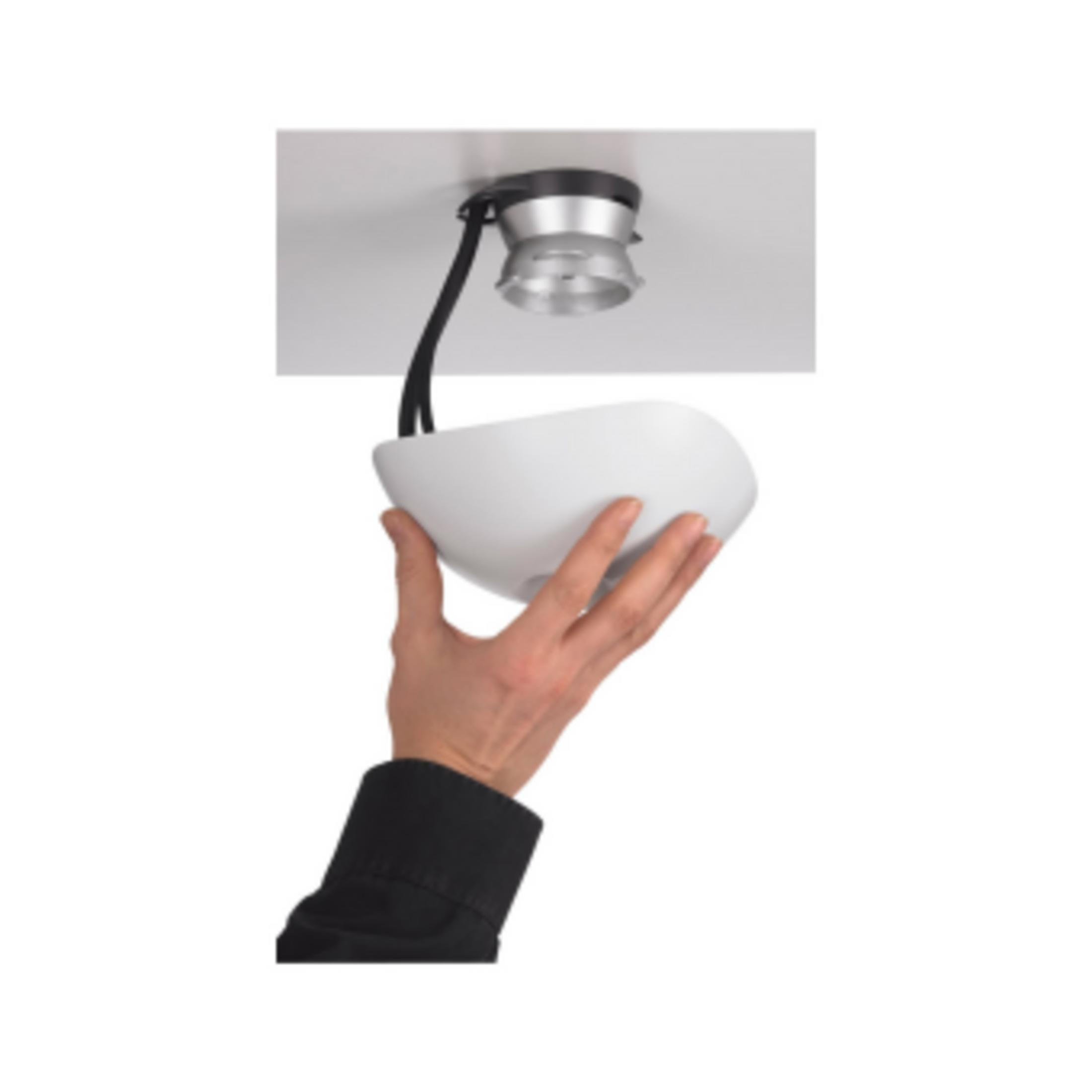 Ręka trzyma białą lampę pod uchwytem sufitowym.