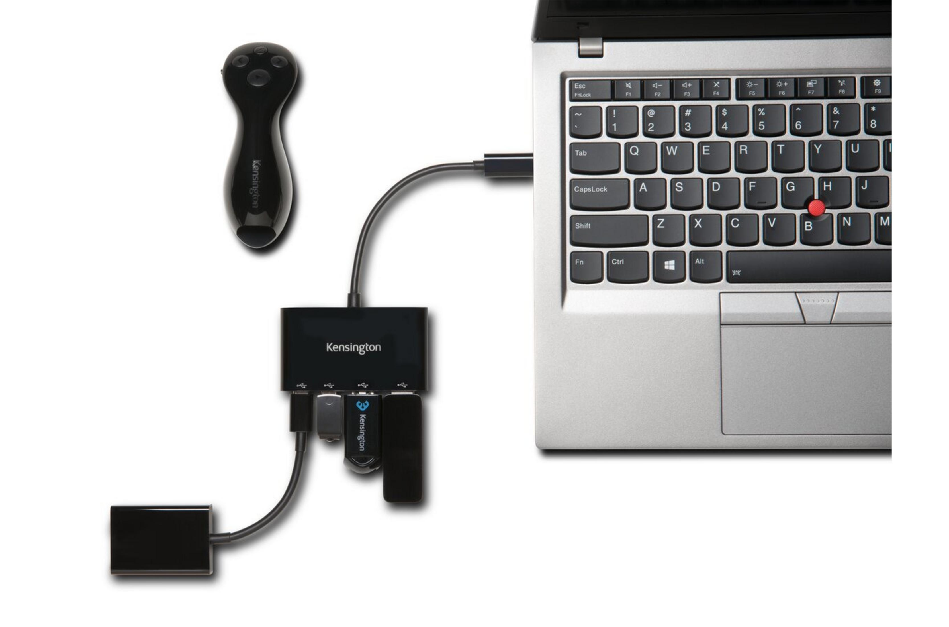 Hub USB Kensington negro con dispositivos conectados y un portátil.