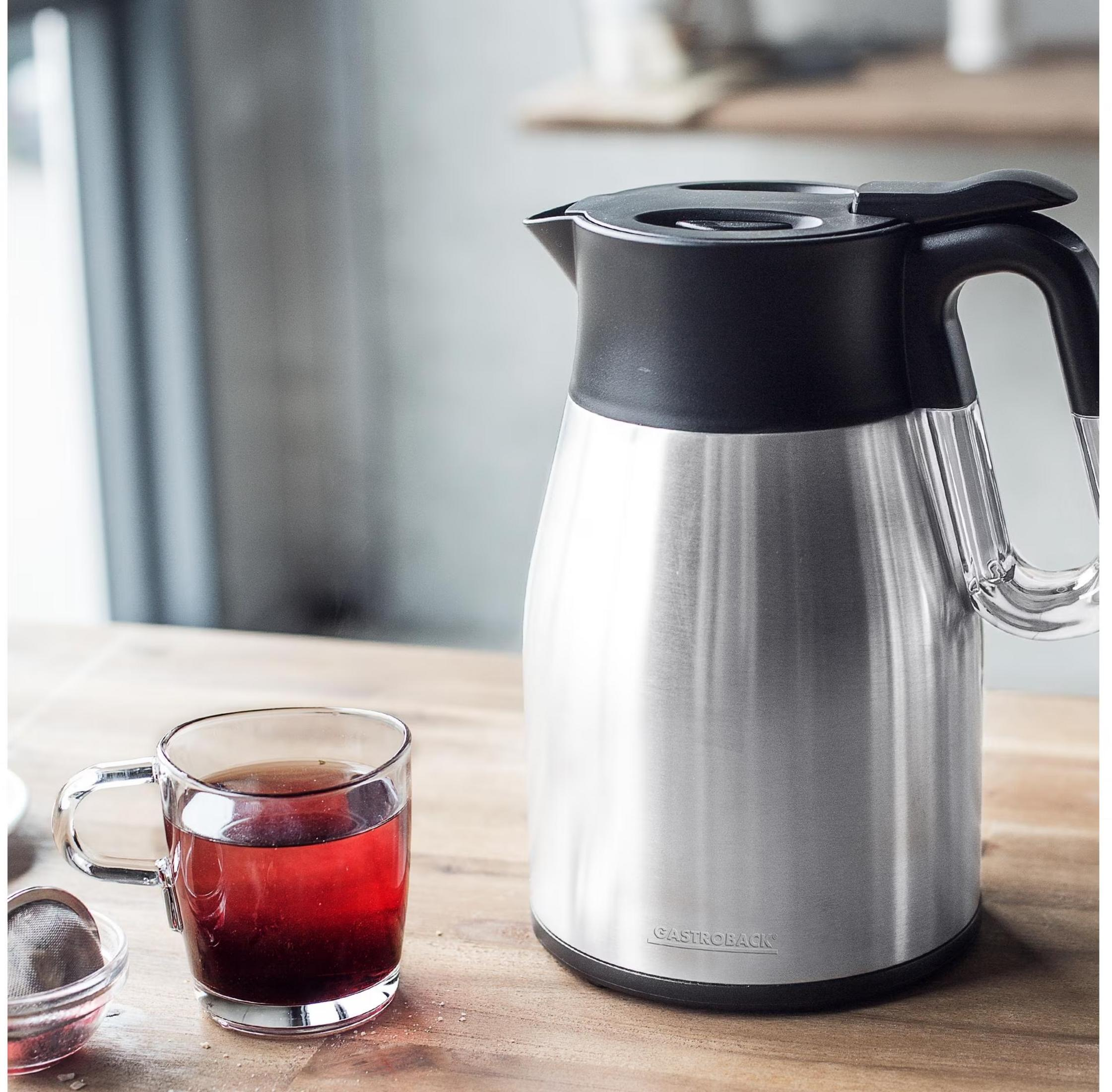 Eine Thermoskanne und eine Tasse mit rotem Tee auf einem Holztisch.