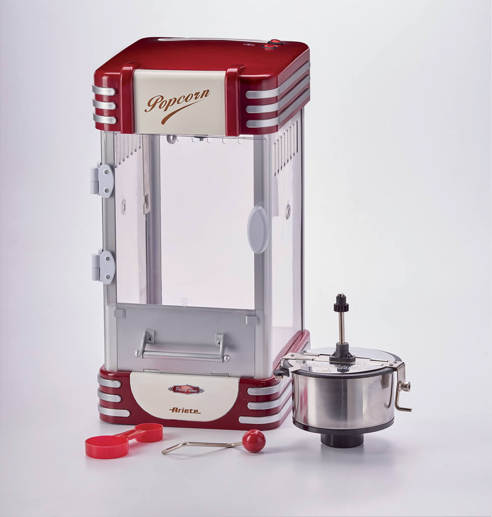 Macchina per popcorn retrò rossa e argento con accessori su sfondo bianco.