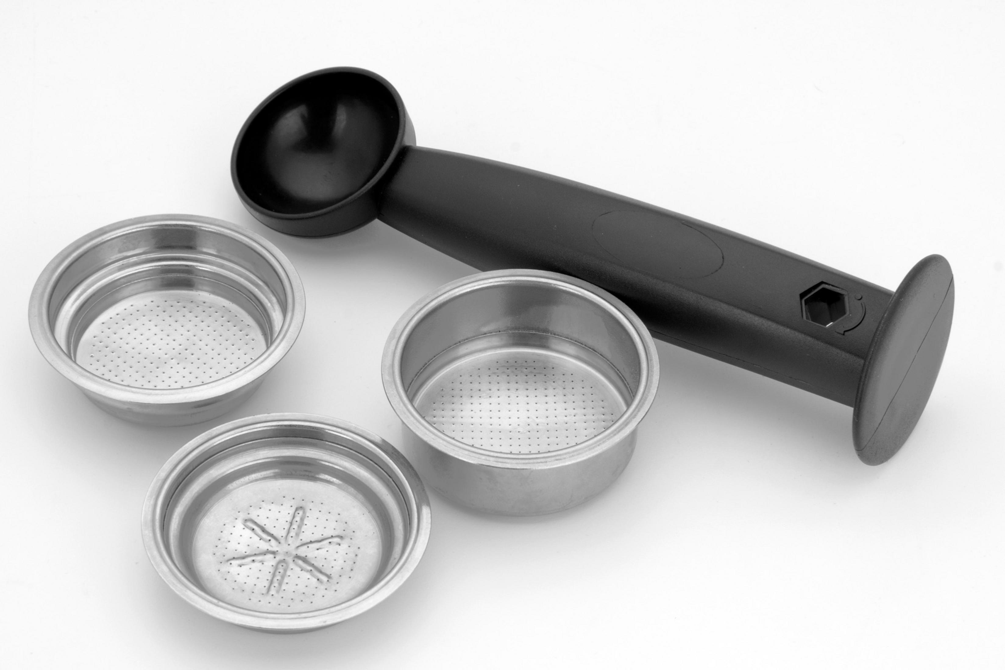 Czarna łyżka i trzy metalowe sitka do espresso na białym tle.