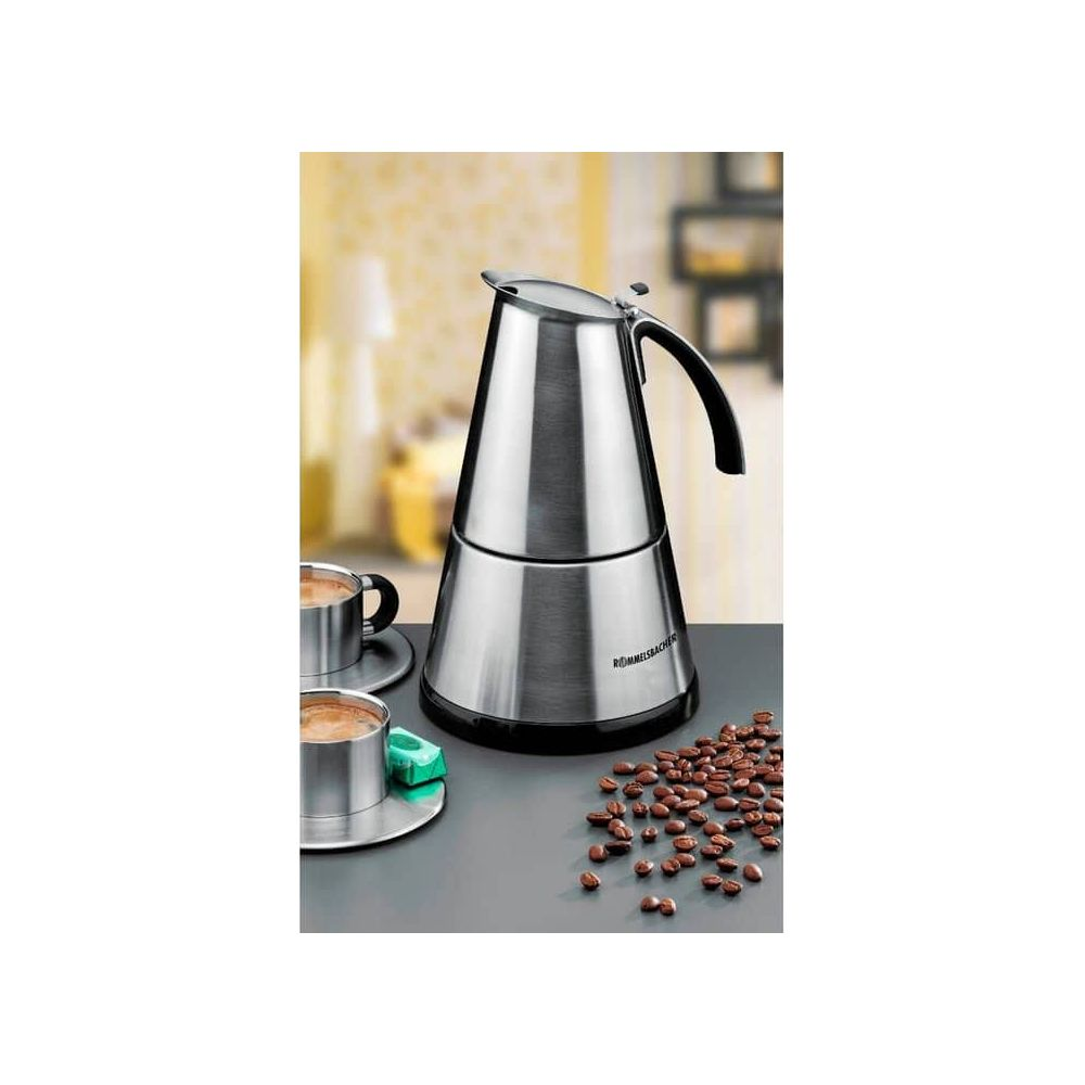 Silberne Kaffeemaschine mit zwei Tassen, Kaffee und Bohnen auf einem Tisch.