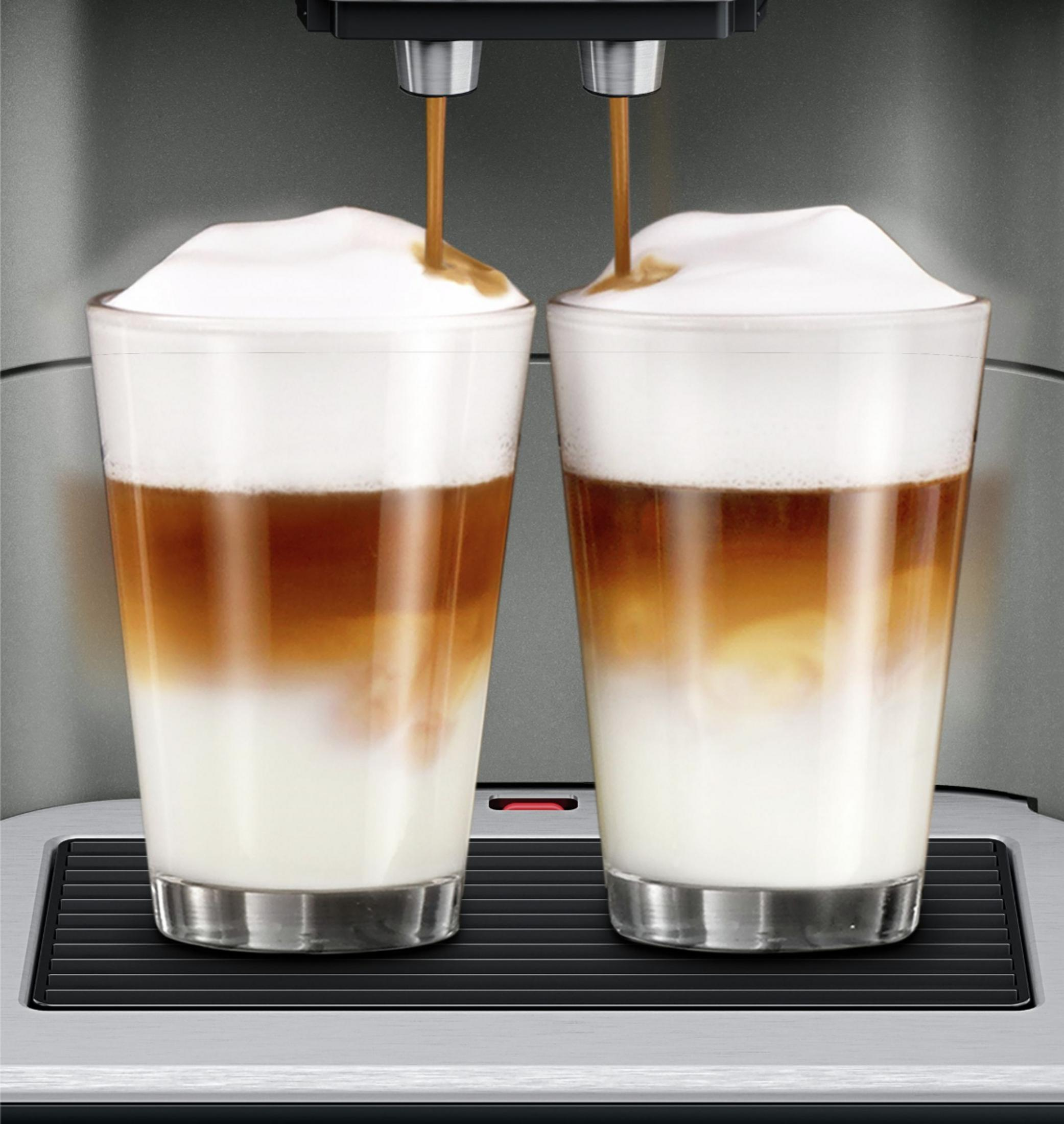 Zwei Gläser Latte Macchiato werden von einer Kaffeemaschine zubereitet.