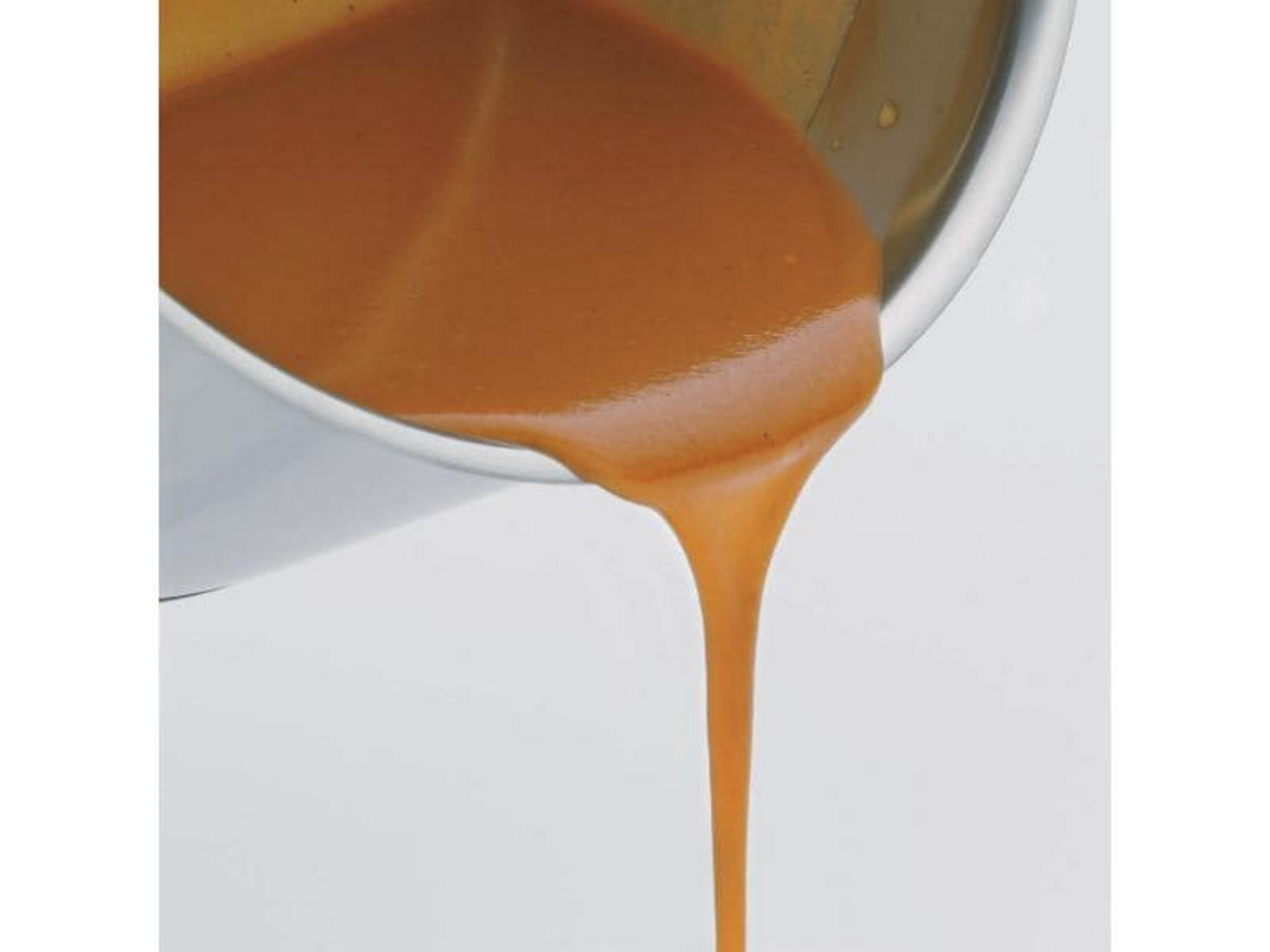 Brązowy sos wypływa z metalowego pojemnika, zbliżenie.