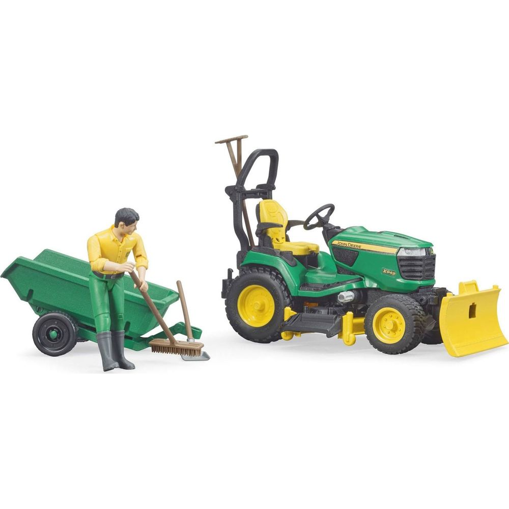Un trattore John Deere verde con aratro giallo accanto a un uomo che spazza vicino a un carrello verde.