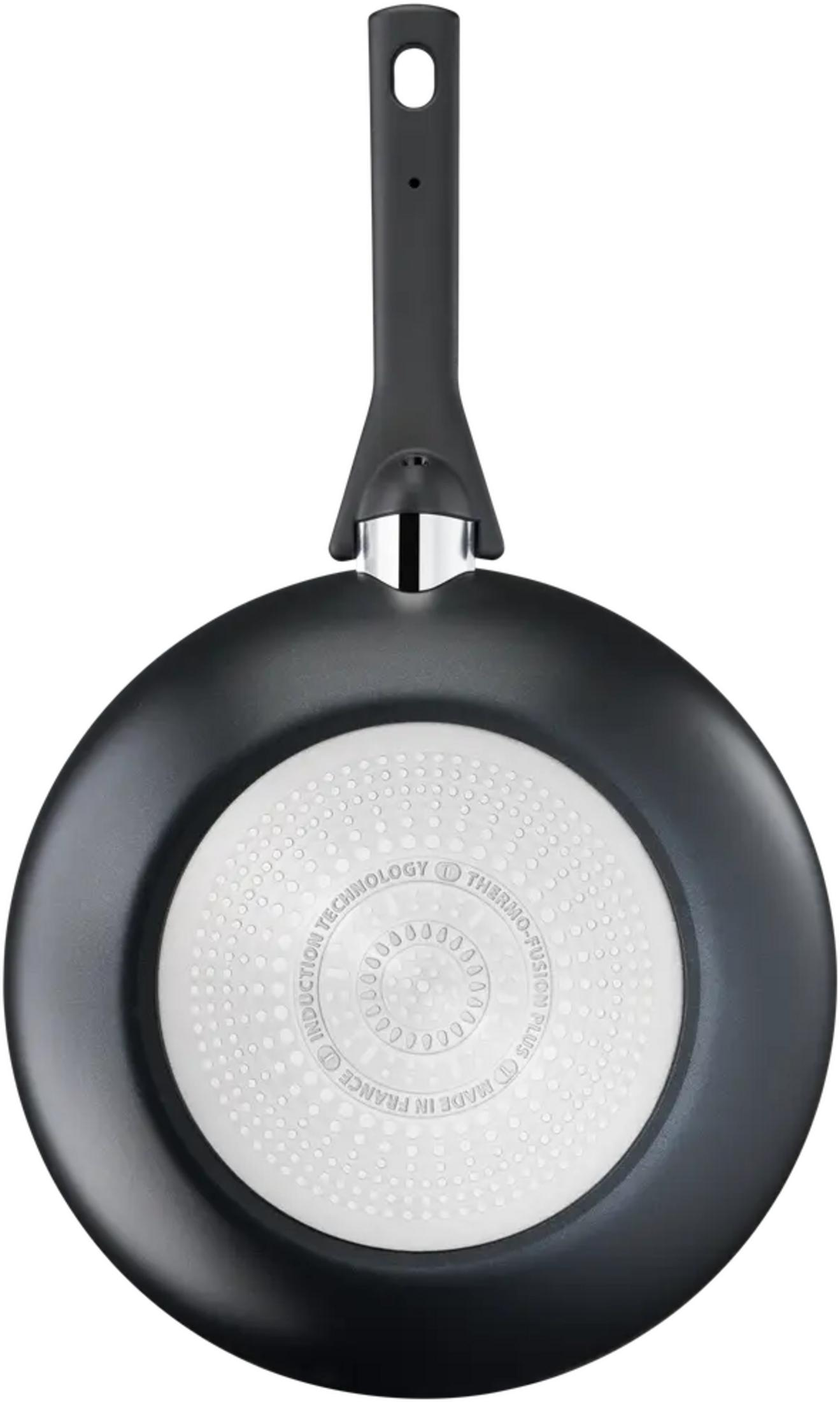 Czarna patelnia z białą, wzorzystą podstawą i czarną rączką. Wyprodukowano we Francji.