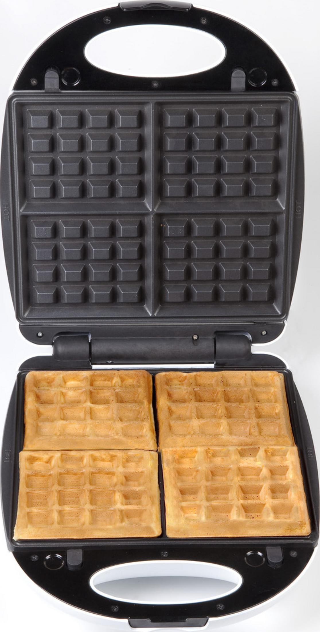 Otwarta gofrownica z czterema upieczonymi goframi na dolnej płycie.