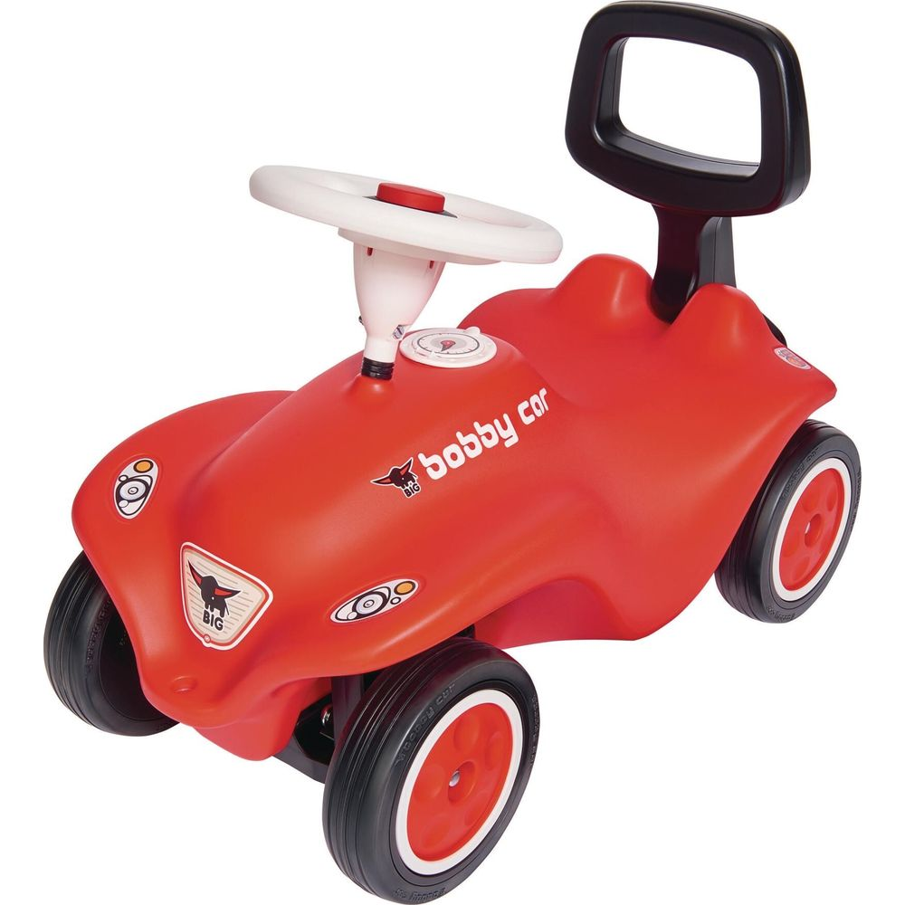 Czerwony jeździk z białym kierownicą i czarną rączką.